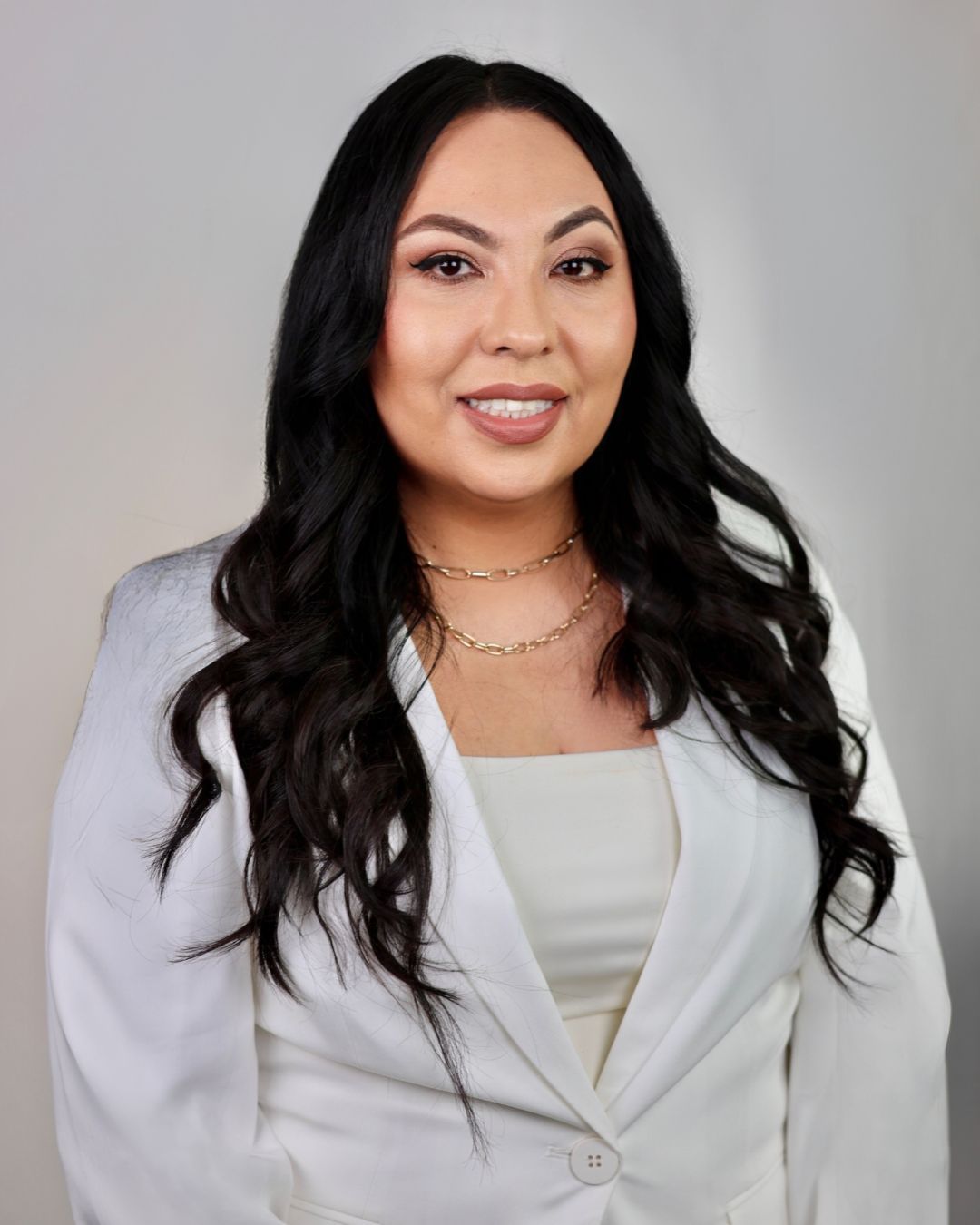A woman is sitting at a desk with a laptop and a vase of flowers.