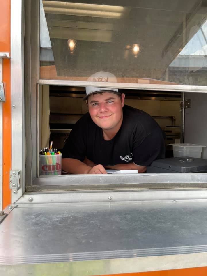 A man is leaning out of a window of a food truck