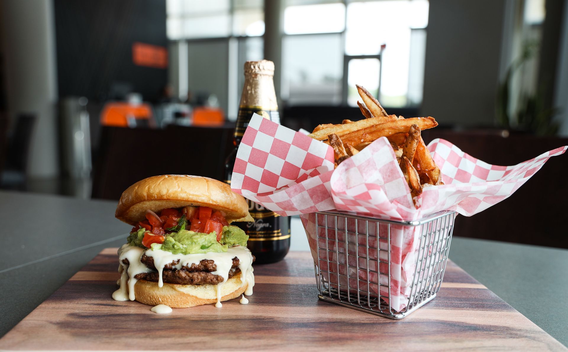 A hamburger and french fries are on a wooden cutting board.