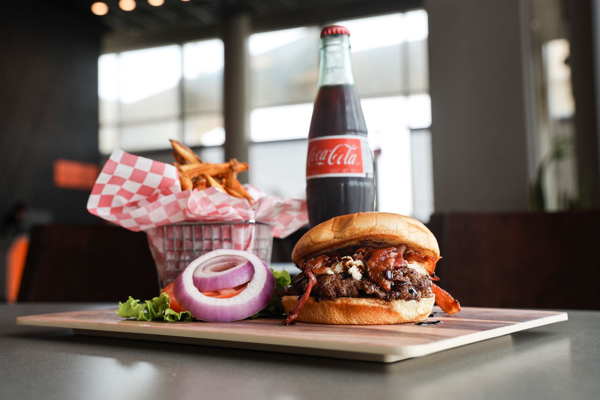 A hamburger and french fries are on a cutting board next to a bottle of coca cola.