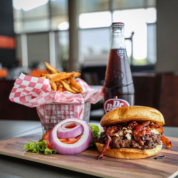 A dr pepper bottle sits next to a hamburger and french fries