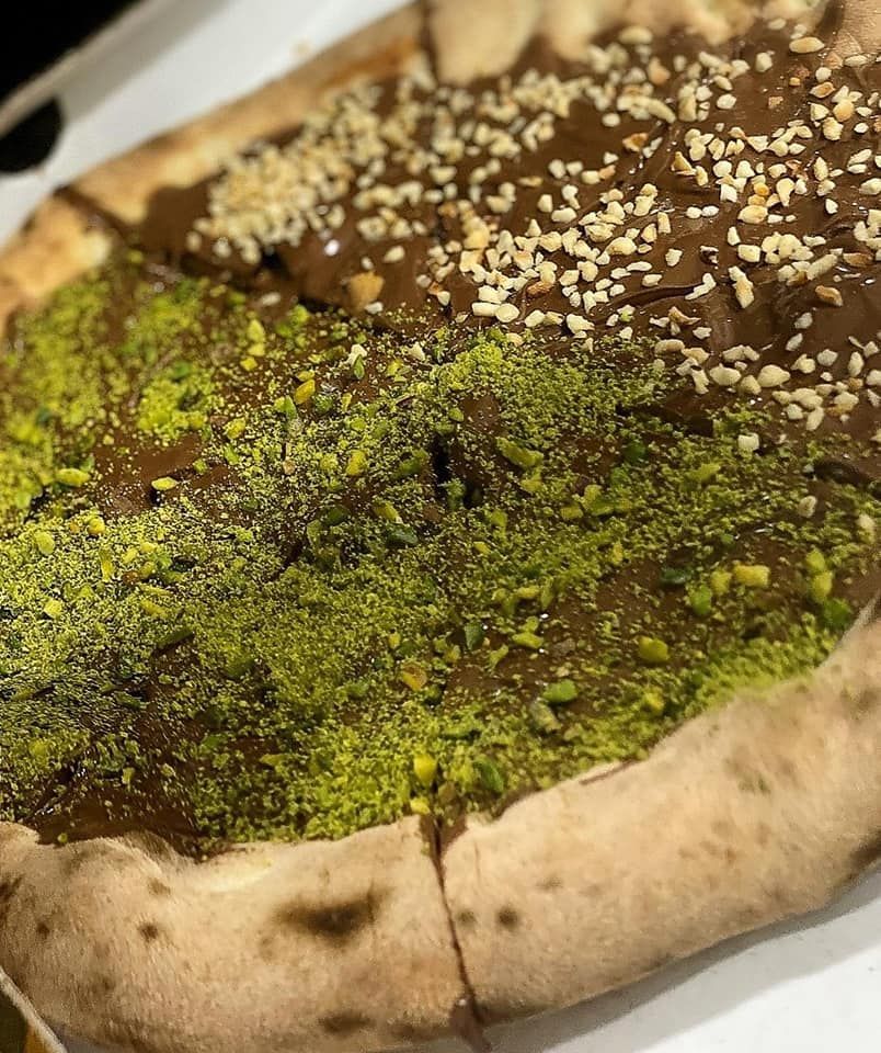 Una pizza con cioccolato e pistacchi è appoggiata su un tavolo.