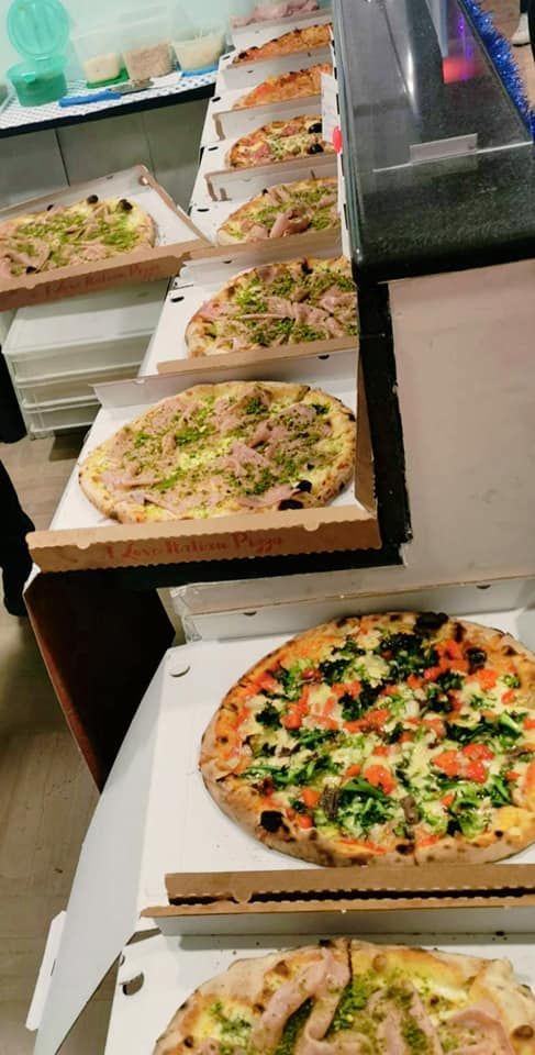 Una fila di pizze sono sistemate una sopra l'altra in scatole di cartone.