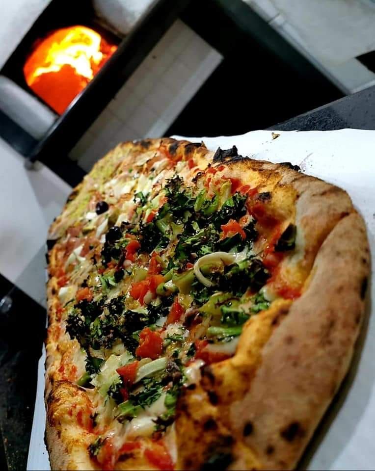 Una pizza è appoggiata su un tavolo davanti a un forno per pizza.
