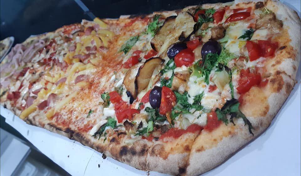 Una pizza molto lunga con tanti condimenti diversi