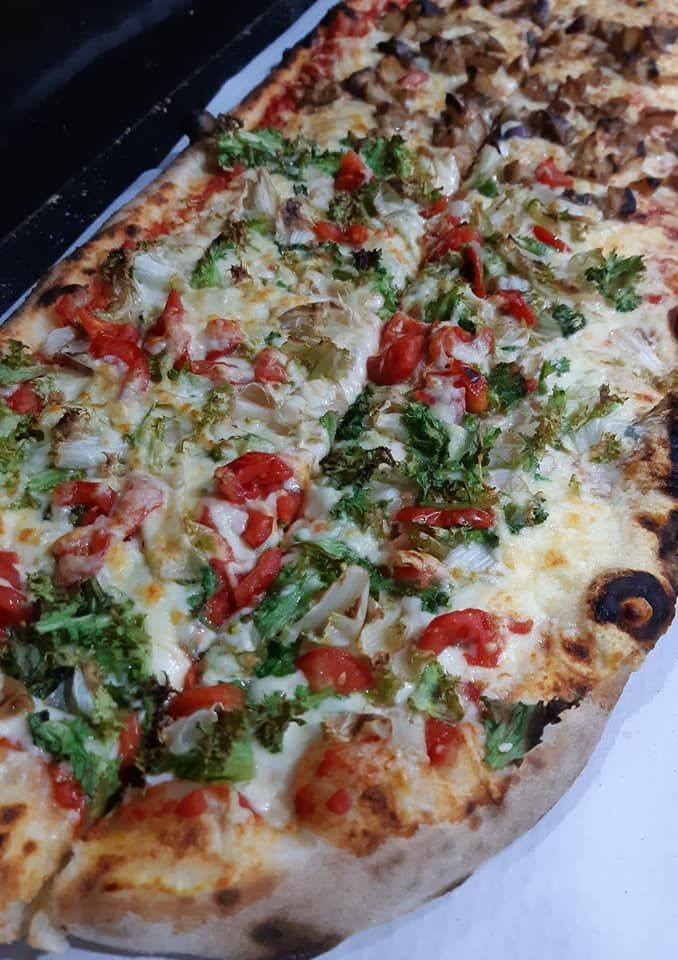 Una pizza con tanti condimenti è appoggiata su un tavolo.