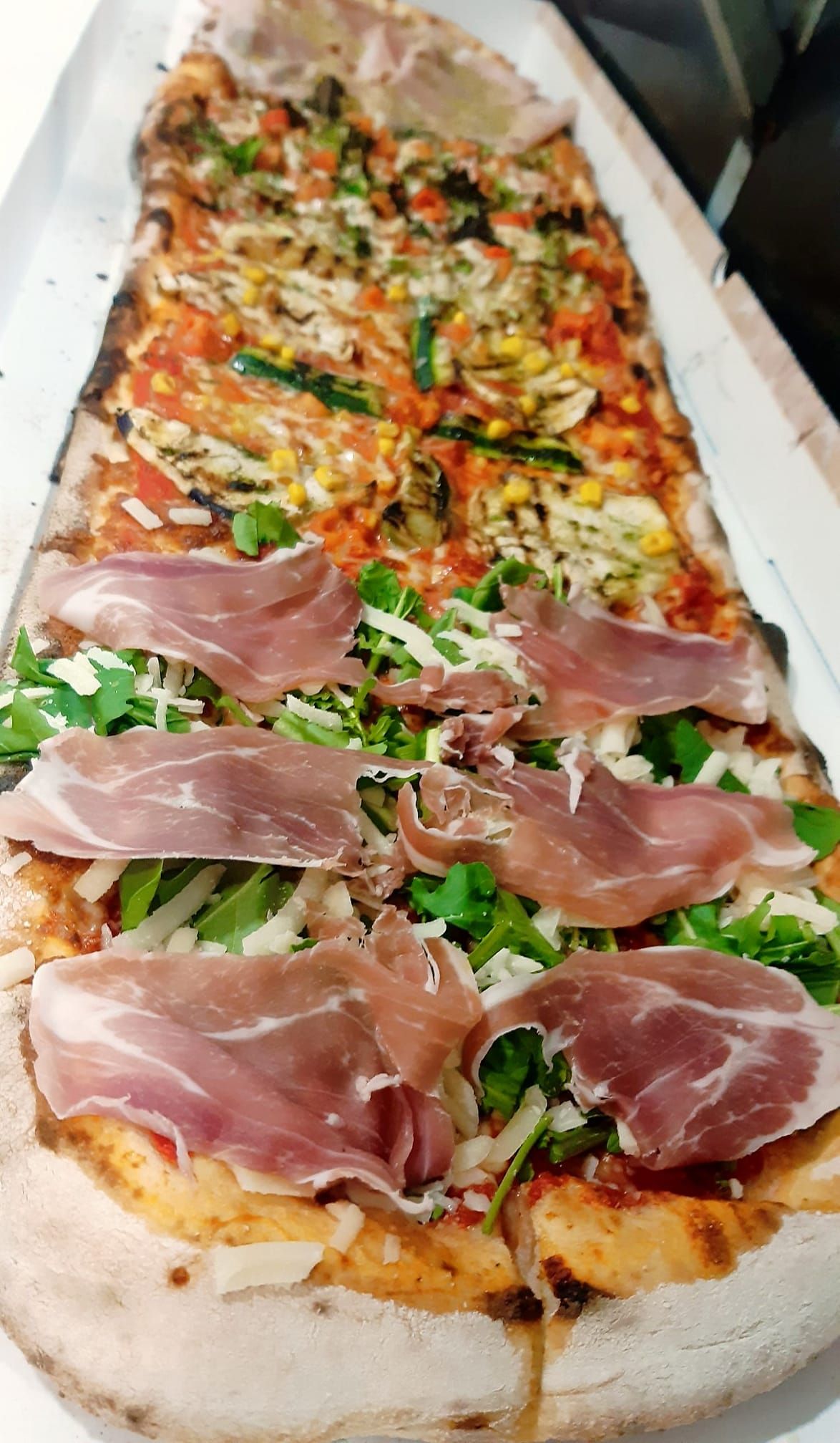 Una pizza con tanti condimenti è appoggiata su un tavolo.