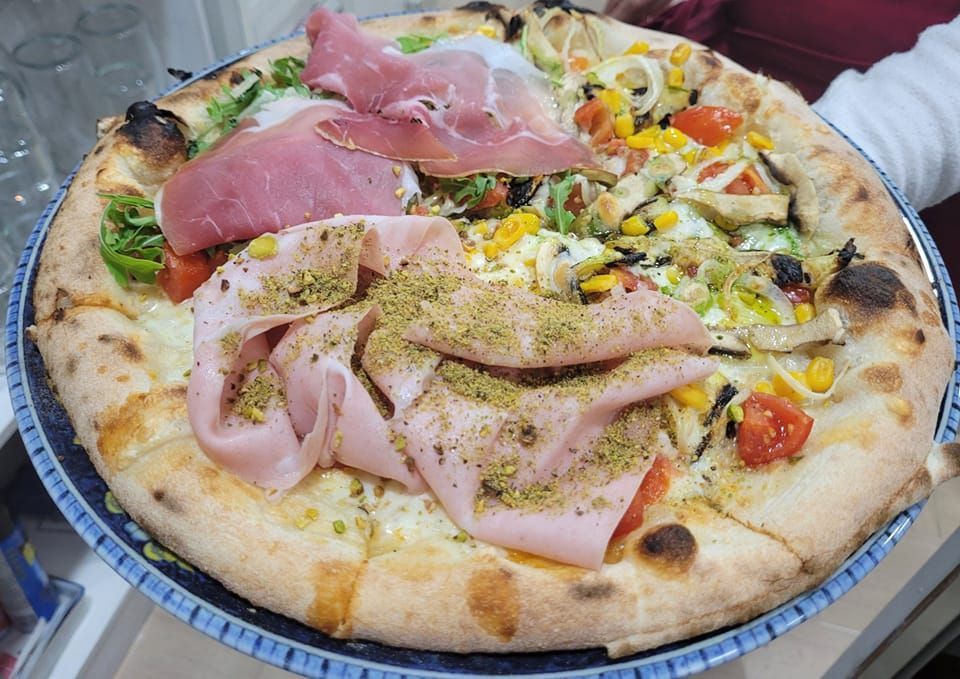 Una pizza con tanti condimenti è su un piatto.