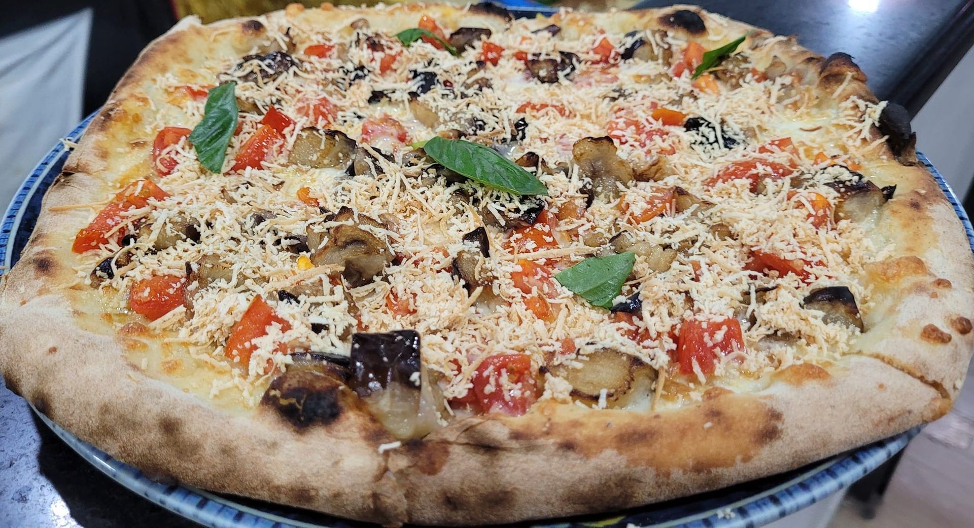 Una pizza con tanti condimenti è su un piatto.