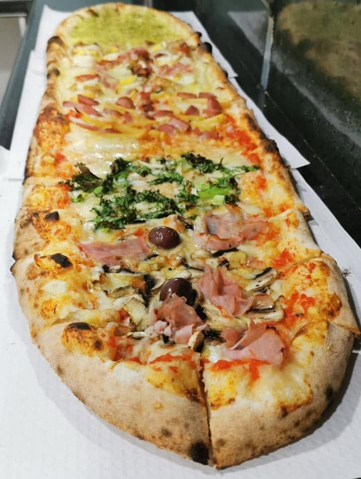 Una pizza molto lunga con molti condimenti sopra