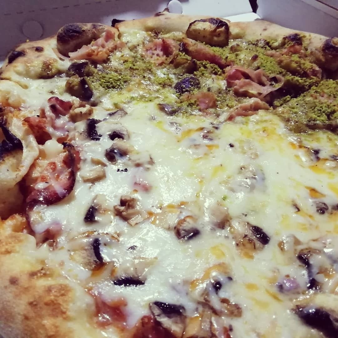 Una pizza con tanti condimenti è in una scatola