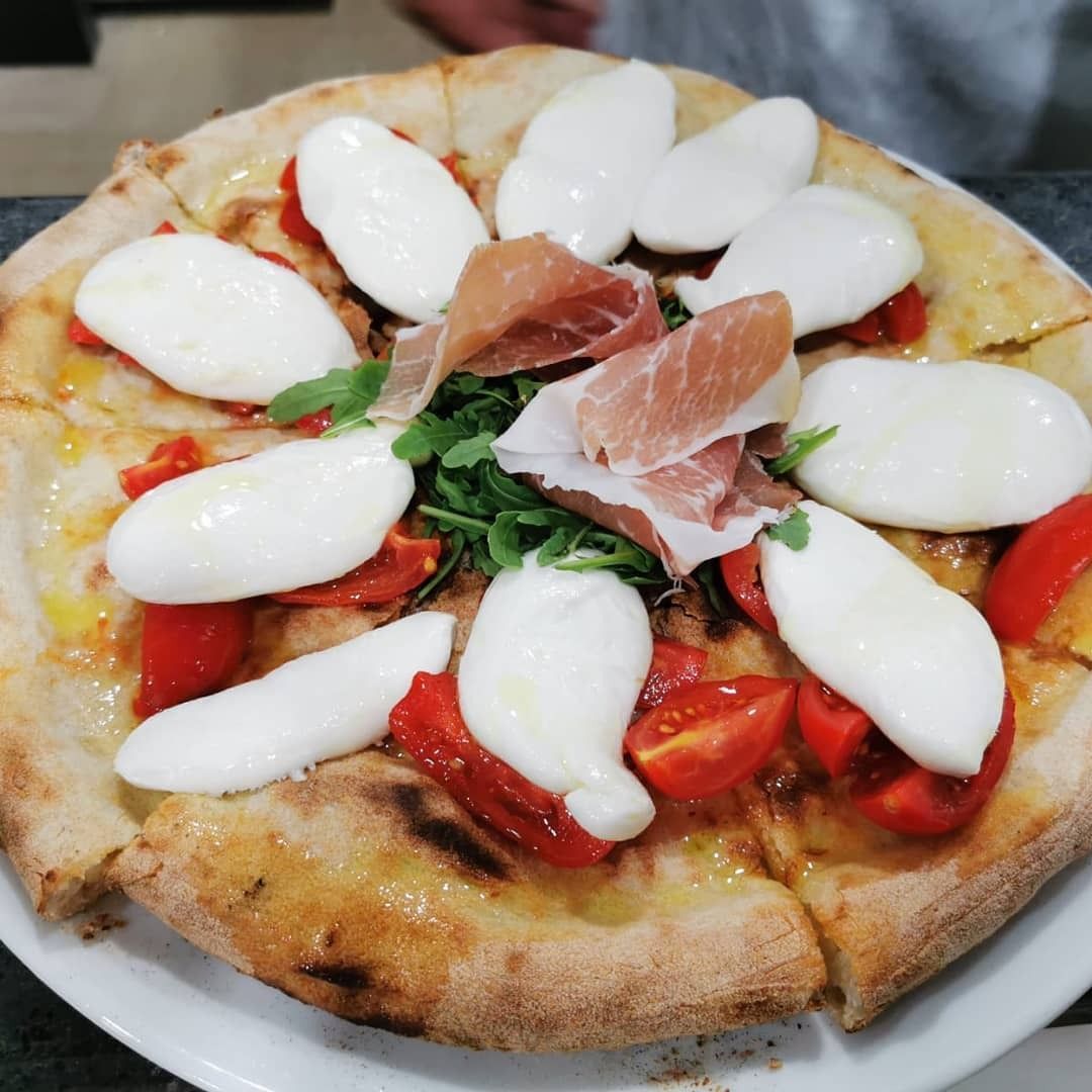 Una pizza con pomodori e mozzarella su un piatto bianco