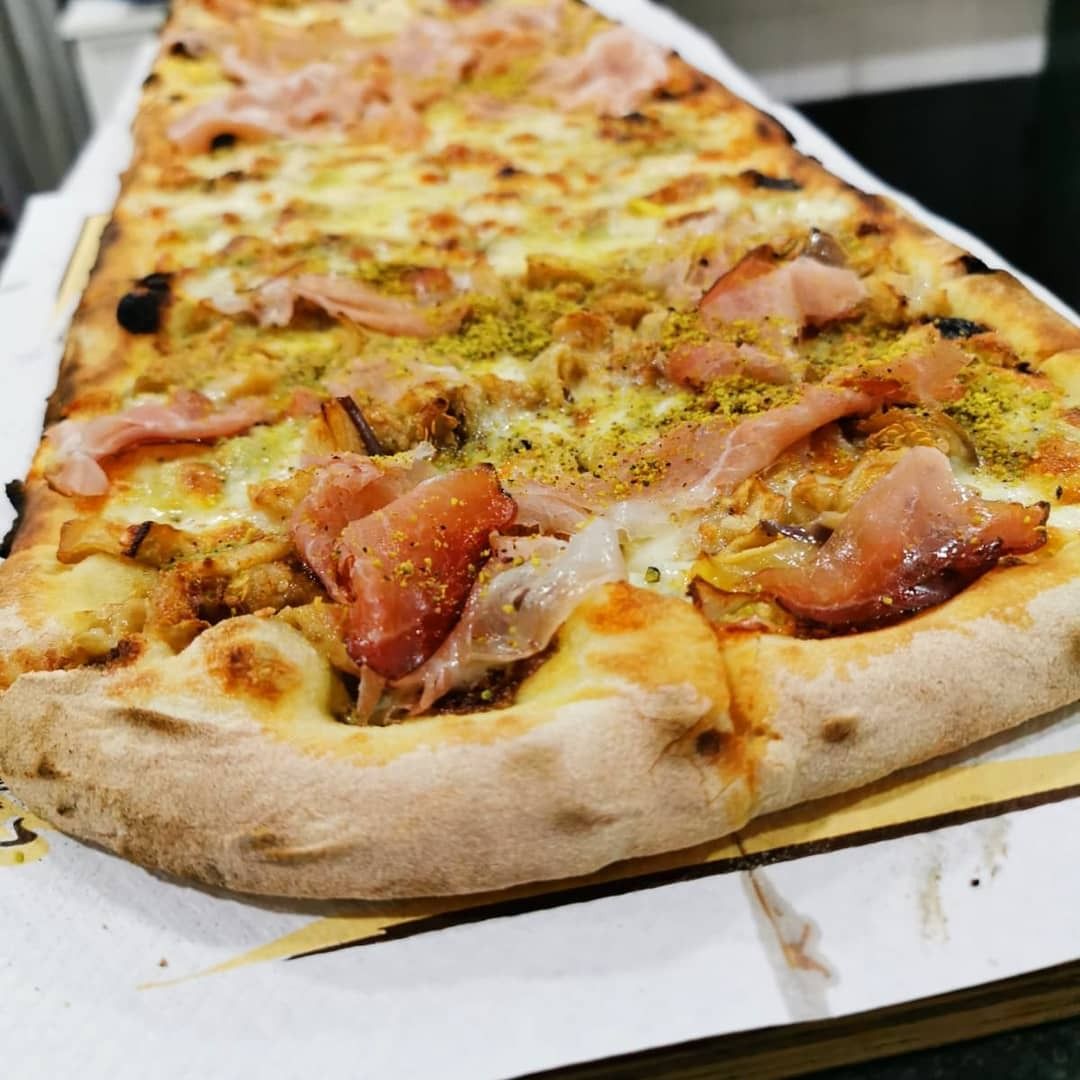 Una pizza molto lunga con molti condimenti sopra