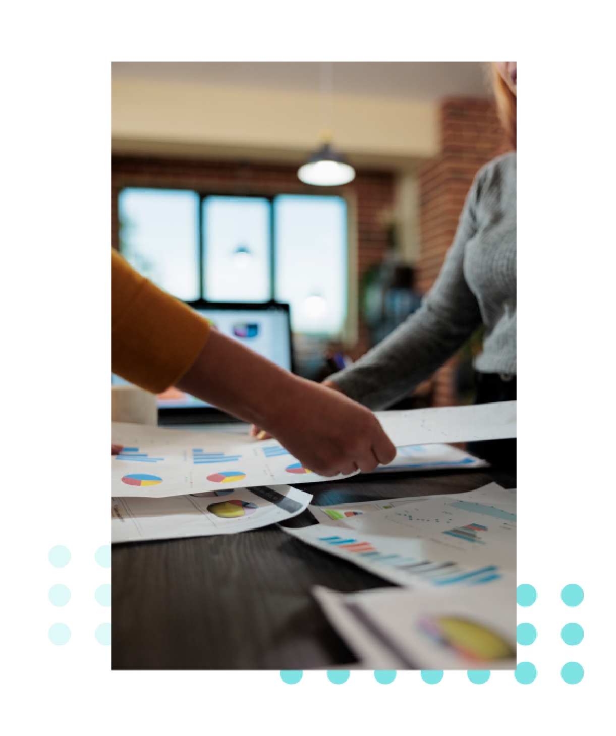 Dos personas revisando gráficos e informes de datos sobre una mesa en un entorno de oficina.