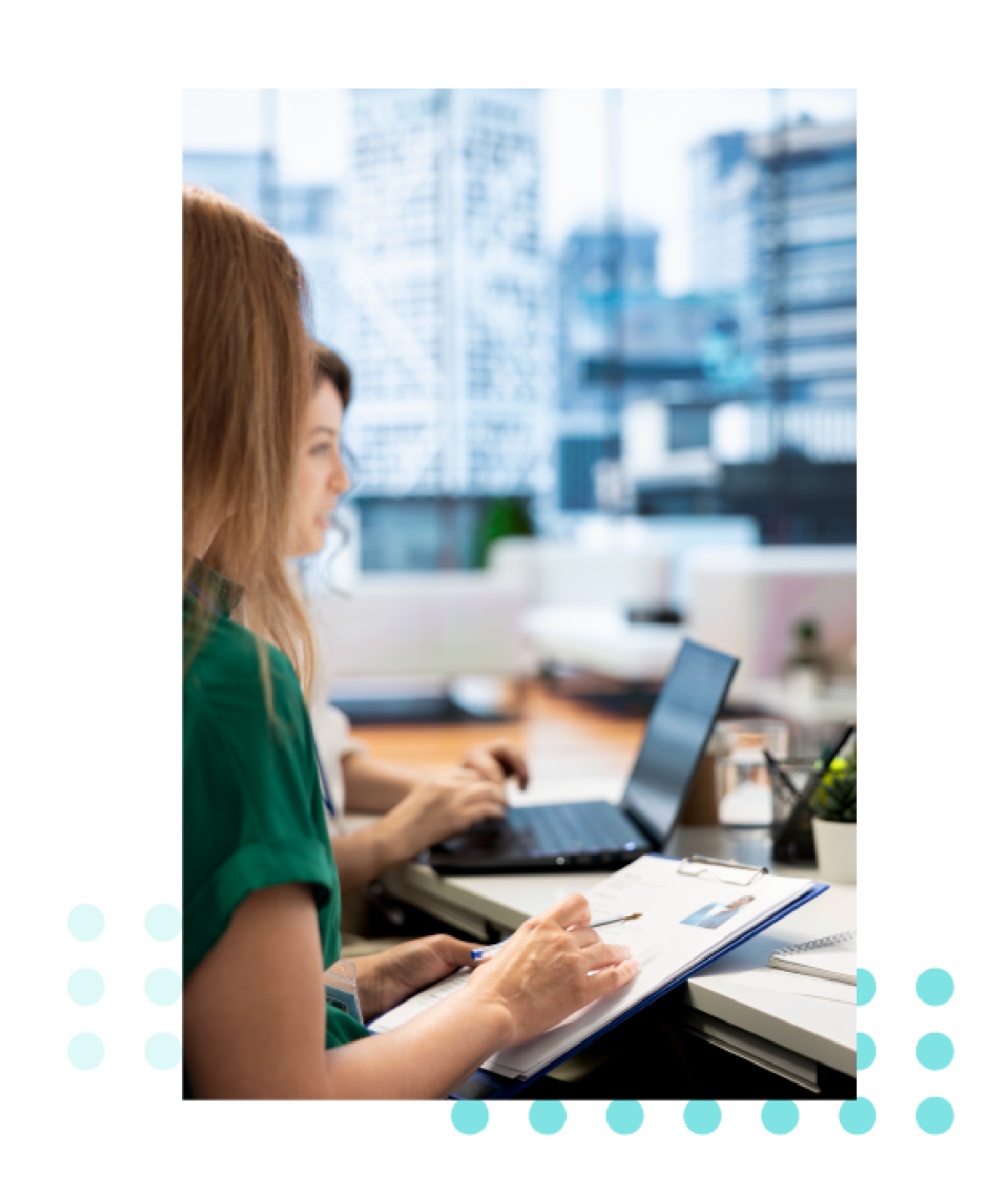 Dos personas trabajan en escritorios en una oficina moderna con grandes ventanales