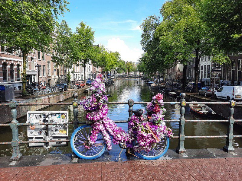 A bike beautiful decorated with flowers parked on a bridge on a canal in Amsterdam