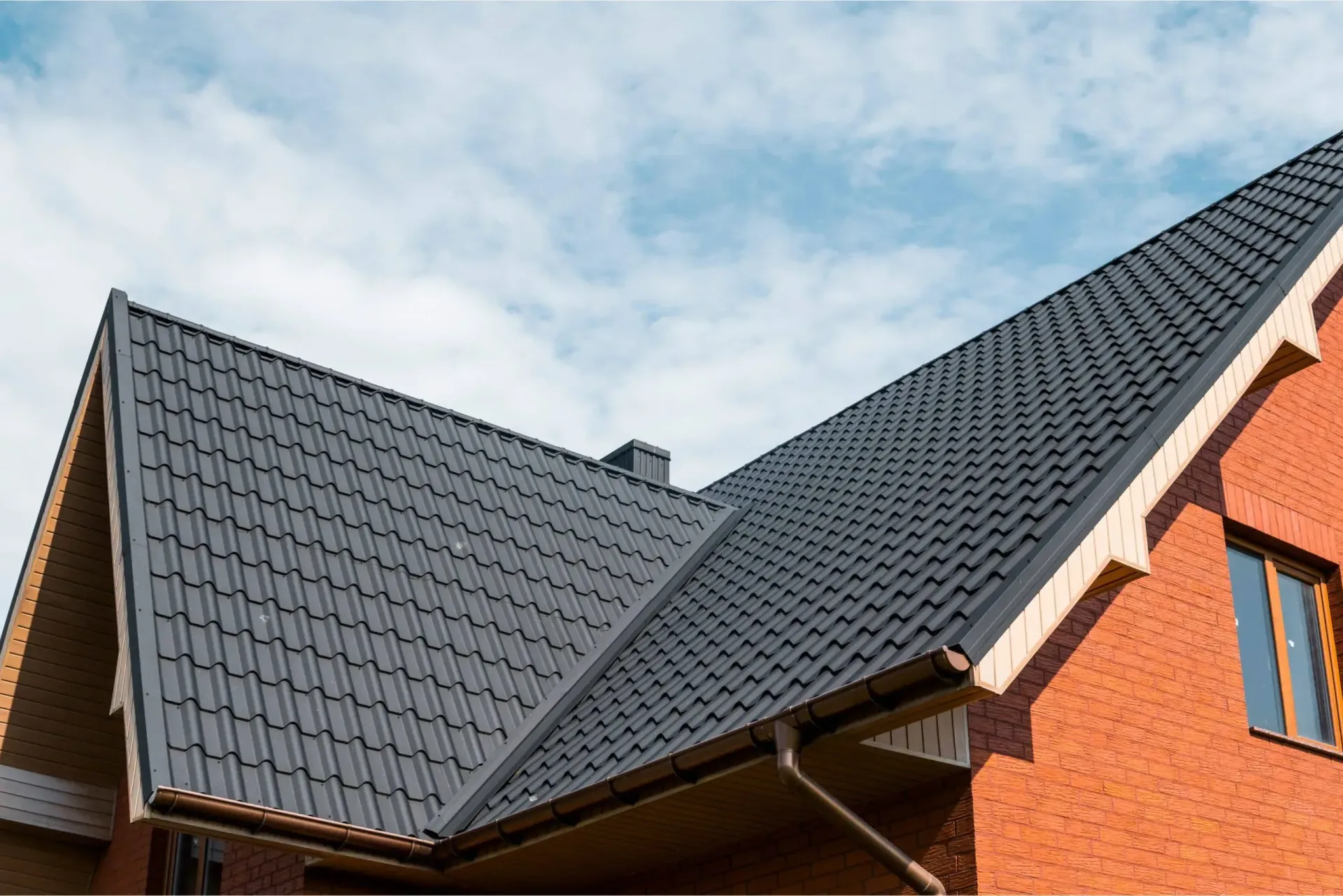 The roof of a red brick house with a black tile roof | Best roofing in Nixa, MO