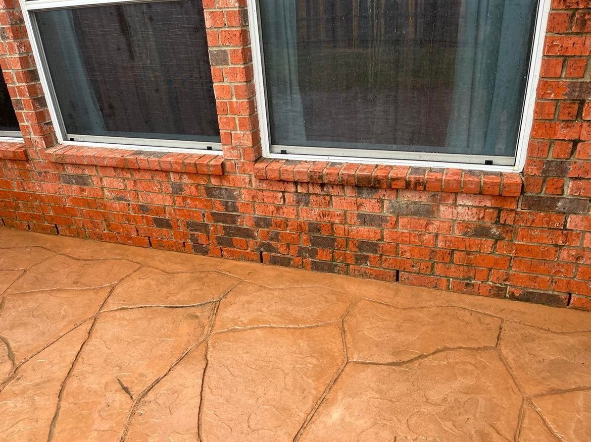 A brick wall with a concrete patio in front of it.