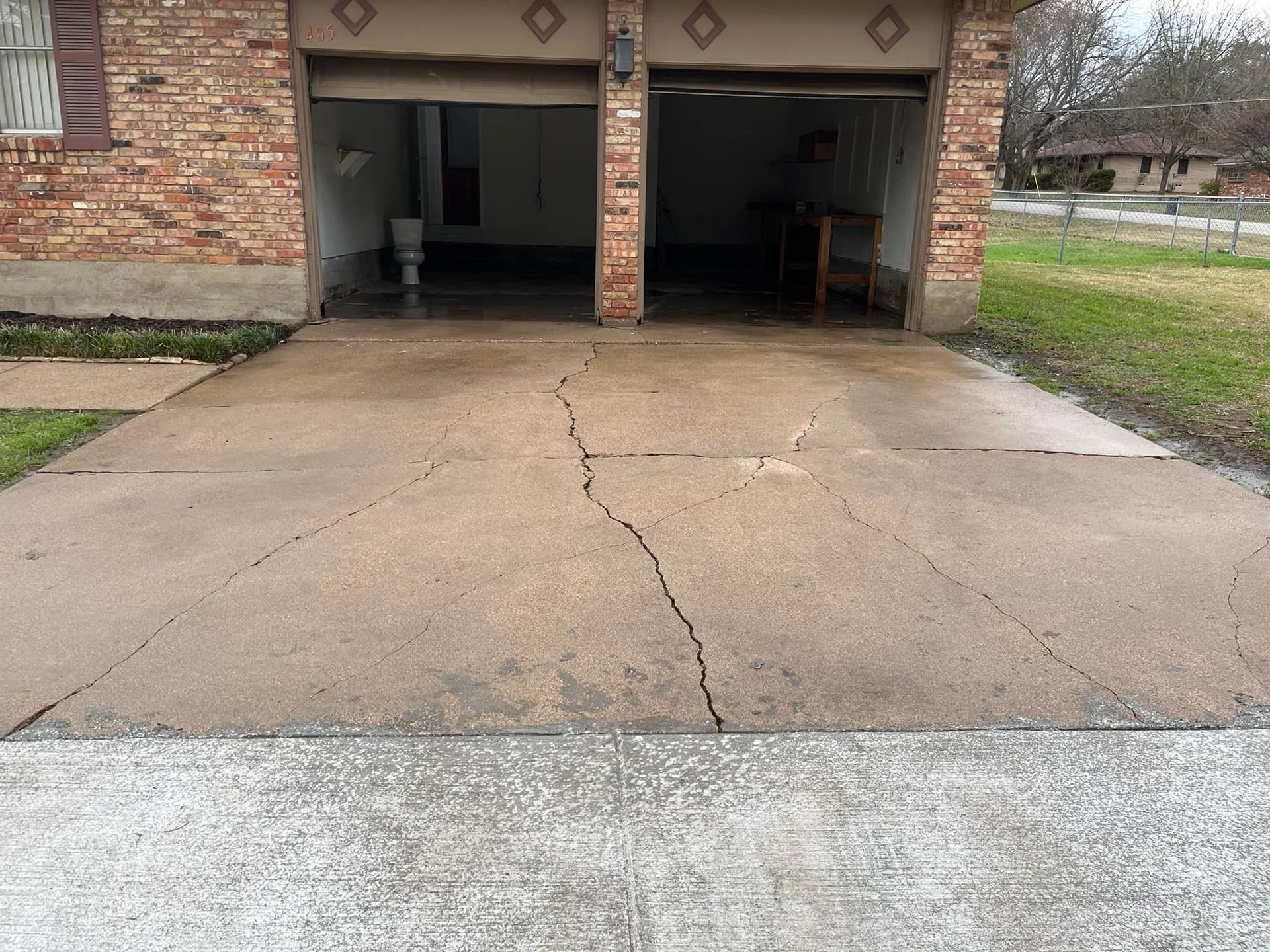 A cracked concrete driveway in front of a garage