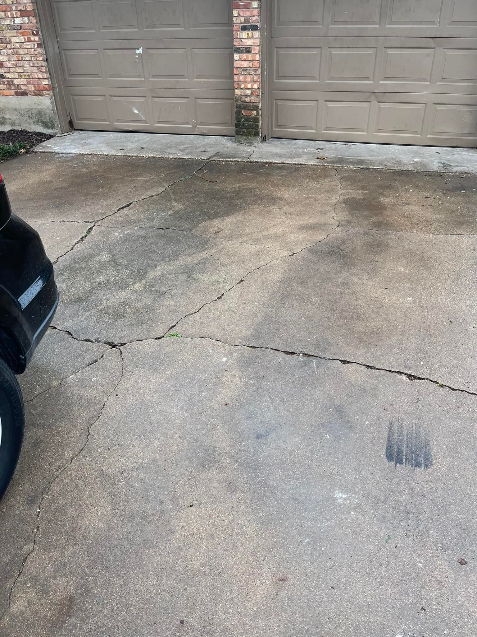 A car is parked in a driveway next to a garage door.