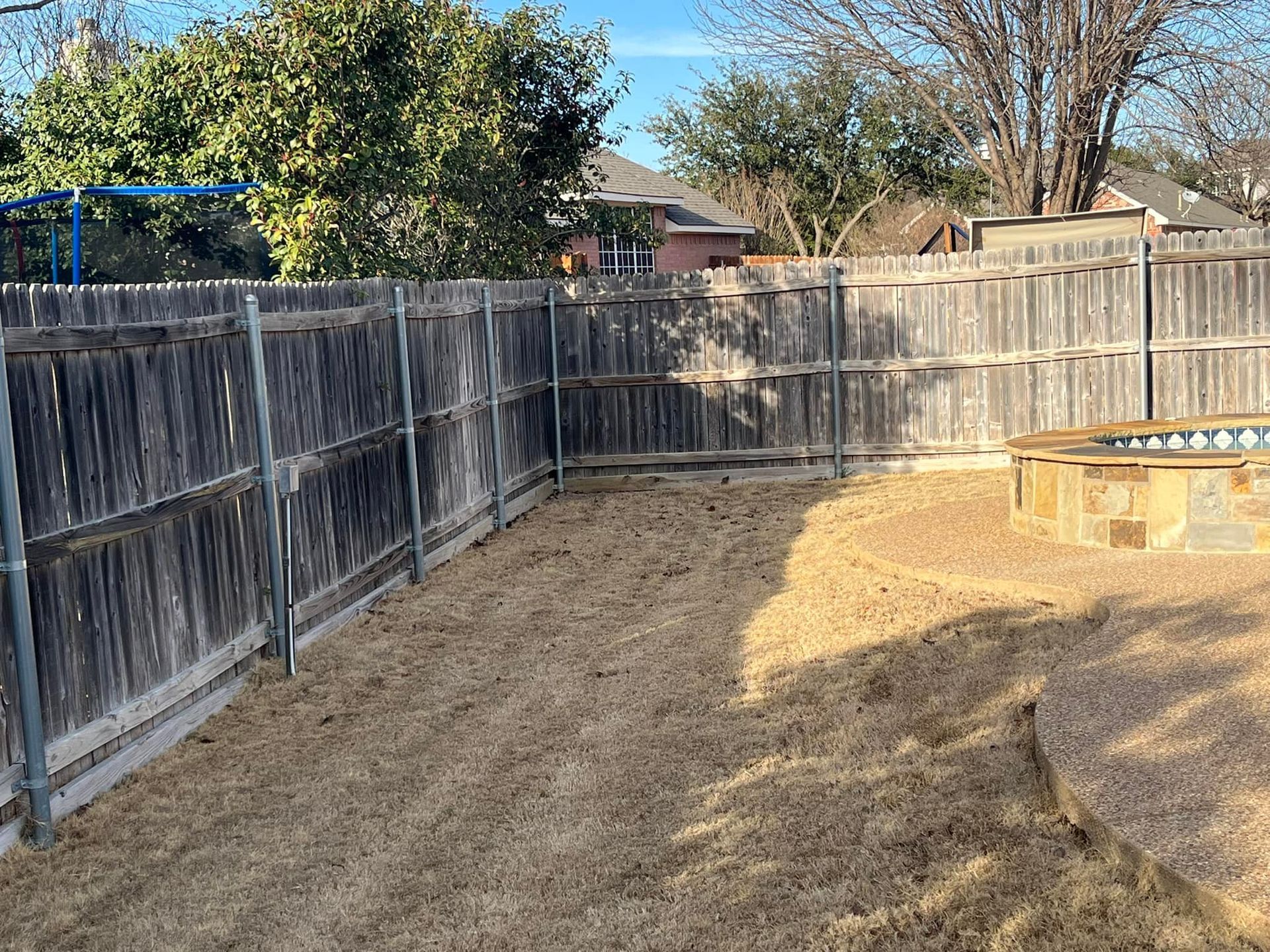 A backyard with a wooden fence and a fire pit.