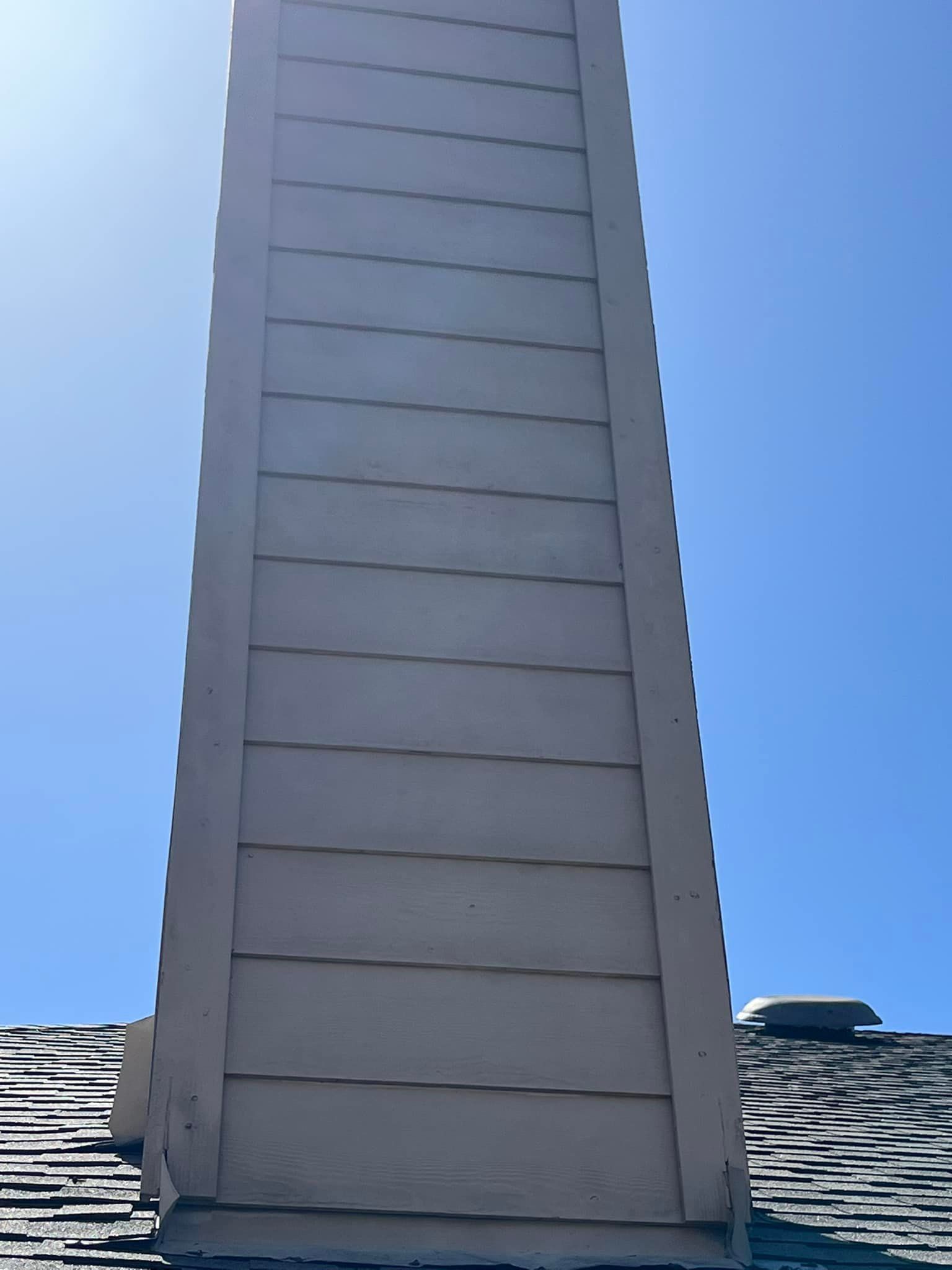 A chimney on top of a roof with a blue sky in the background.