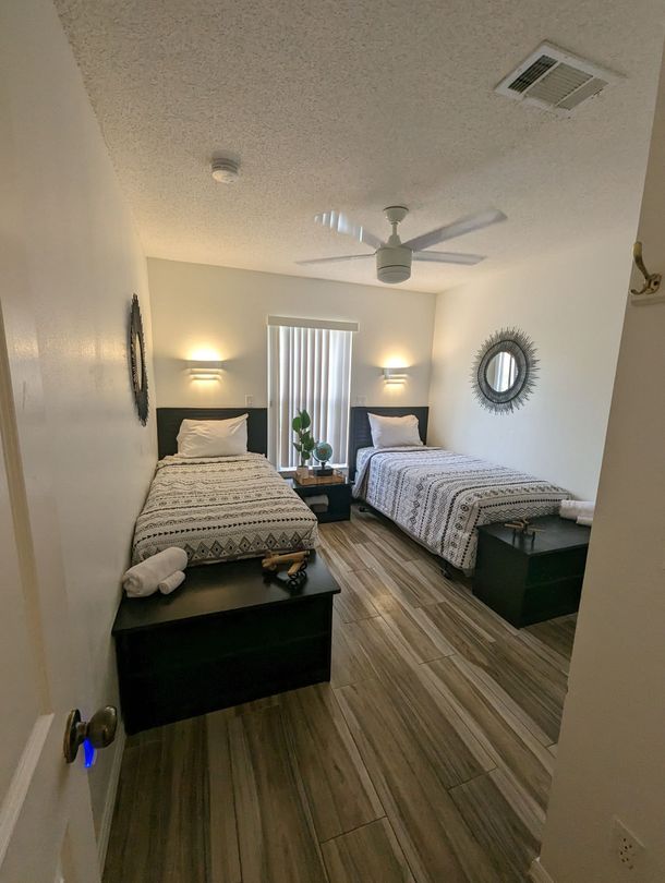 A bedroom with two beds and a ceiling fan.