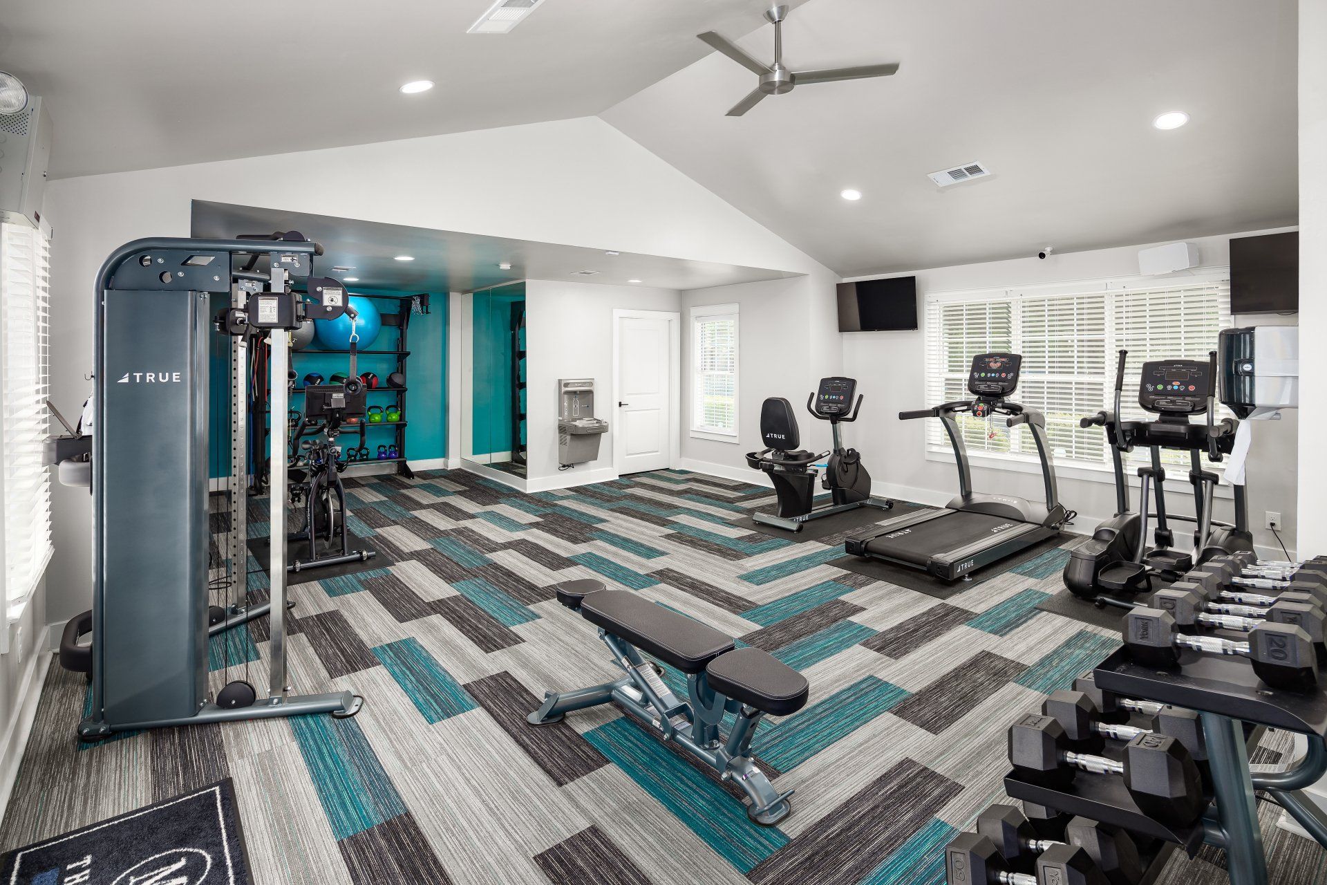 A large gym with a lot of equipment and a ceiling fan.