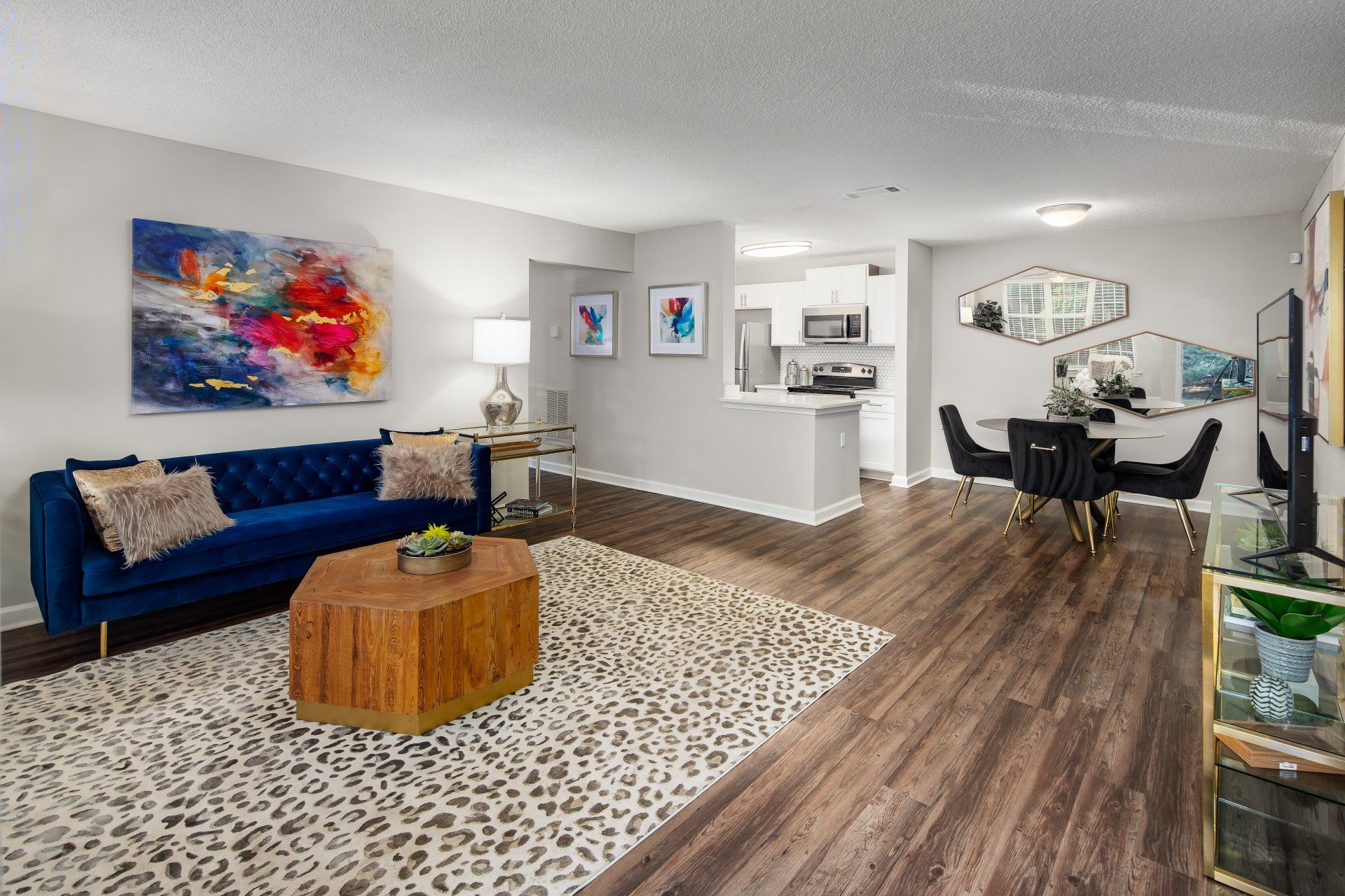 A living room with a blue couch , a coffee table , and a rug.