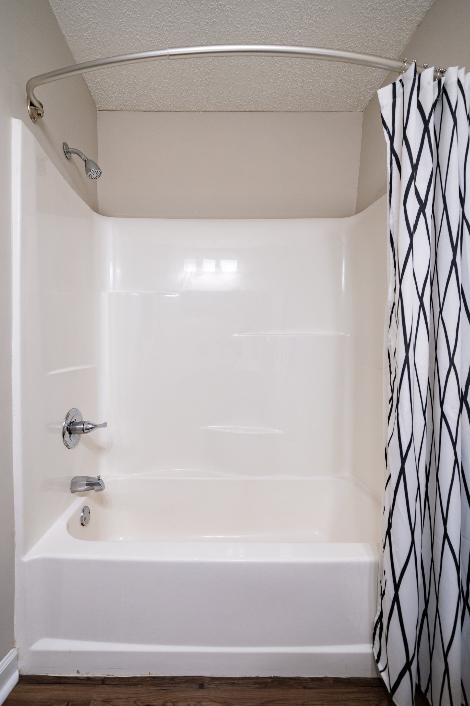 A white bathtub with a black and white shower curtain in a bathroom.