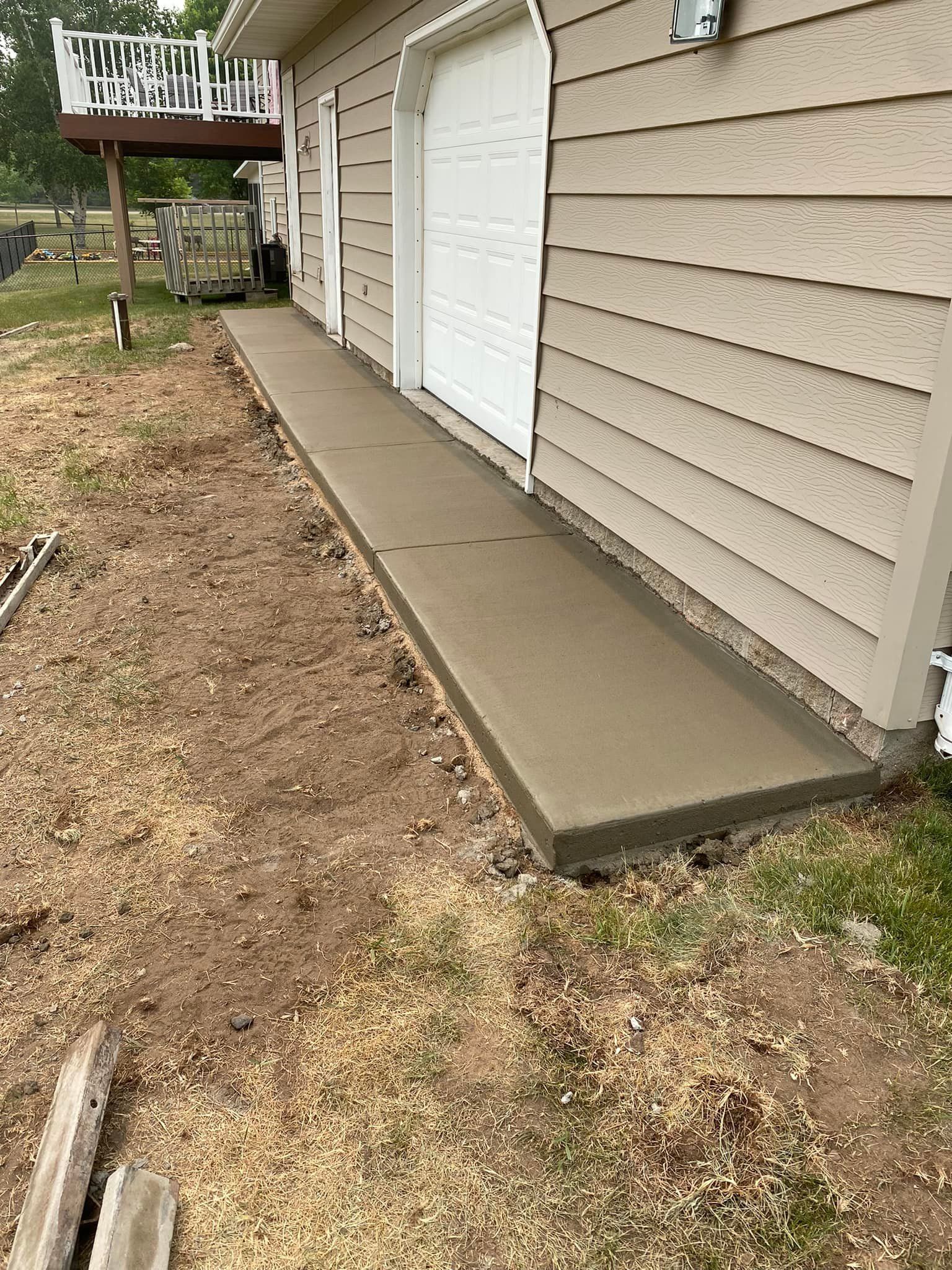 A concrete walkway is being built on the side of a house.