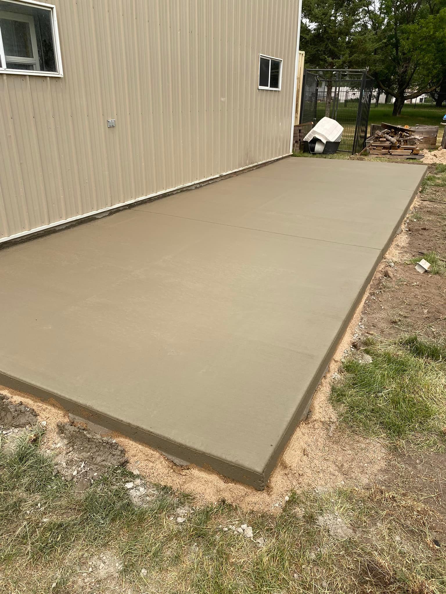 A concrete patio is being built in front of a house.