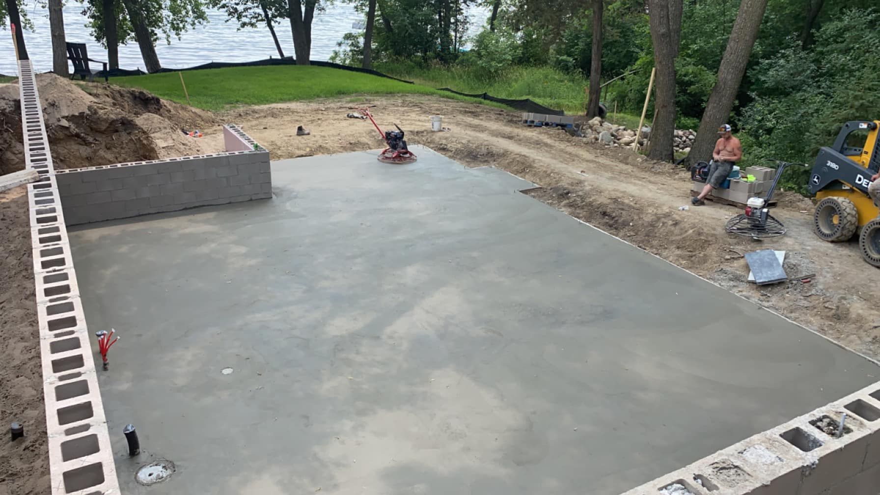 A concrete base for a house is being built next to a lake.