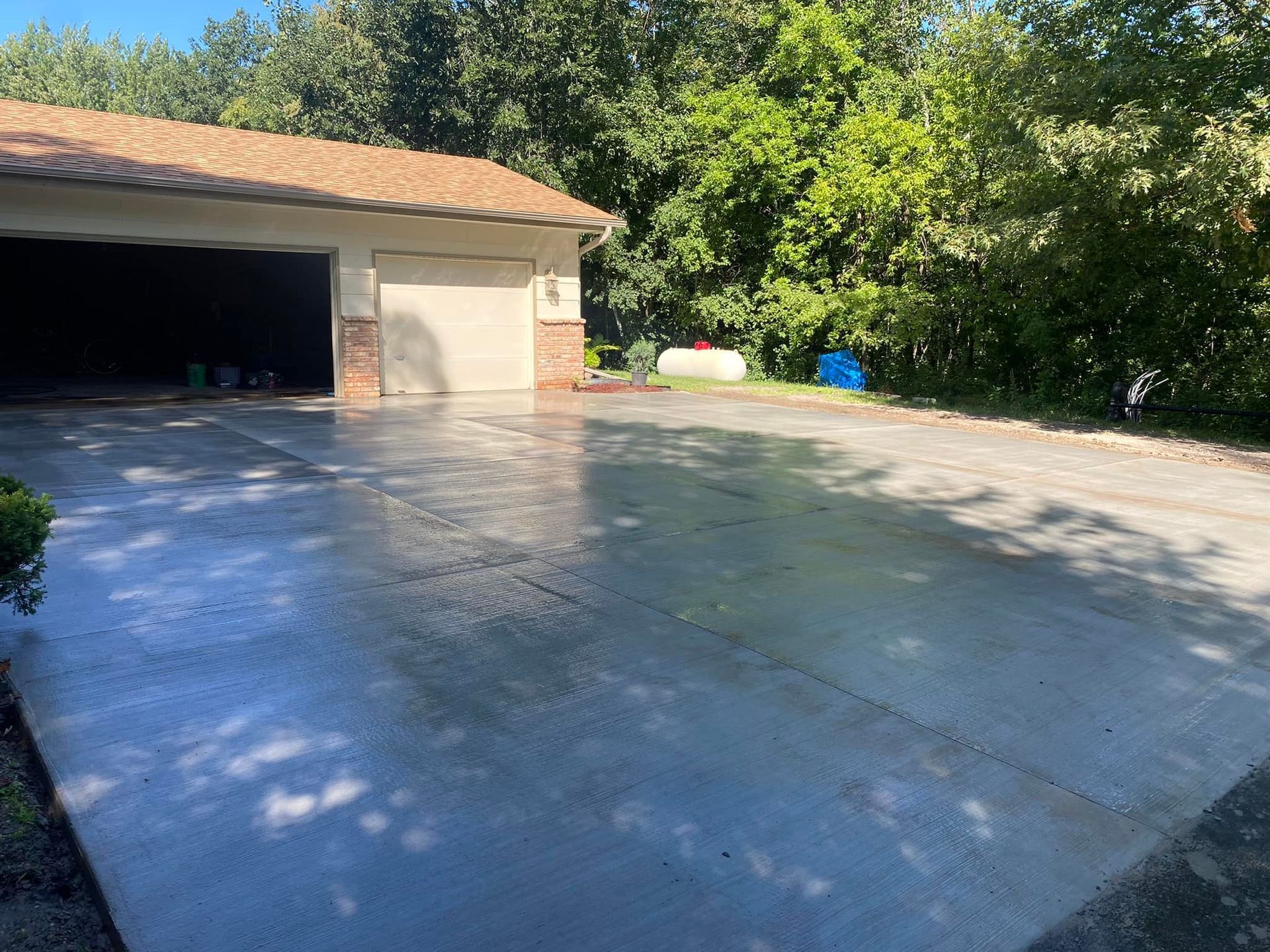 A concrete driveway leading to a garage with trees in the background.