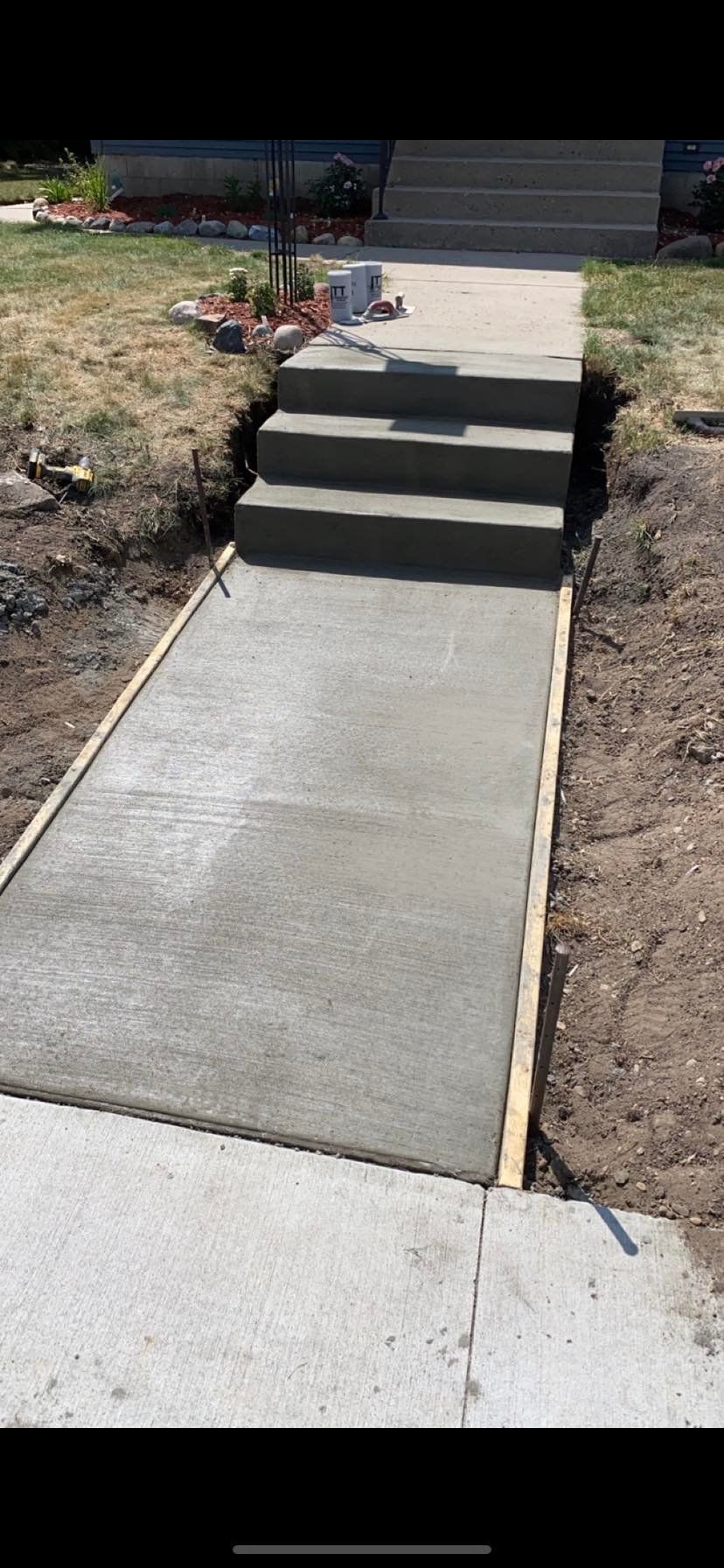 A concrete walkway with stairs going up to a house.