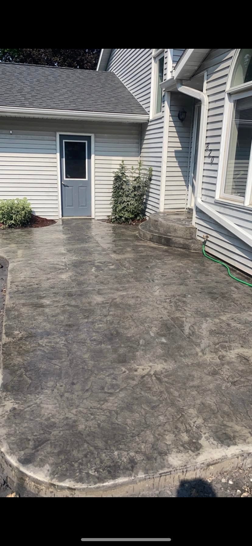 A concrete patio in front of a house with a door.