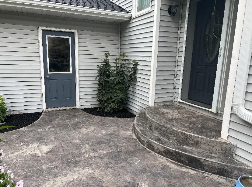 There is a concrete walkway leading to the front door of a house.
