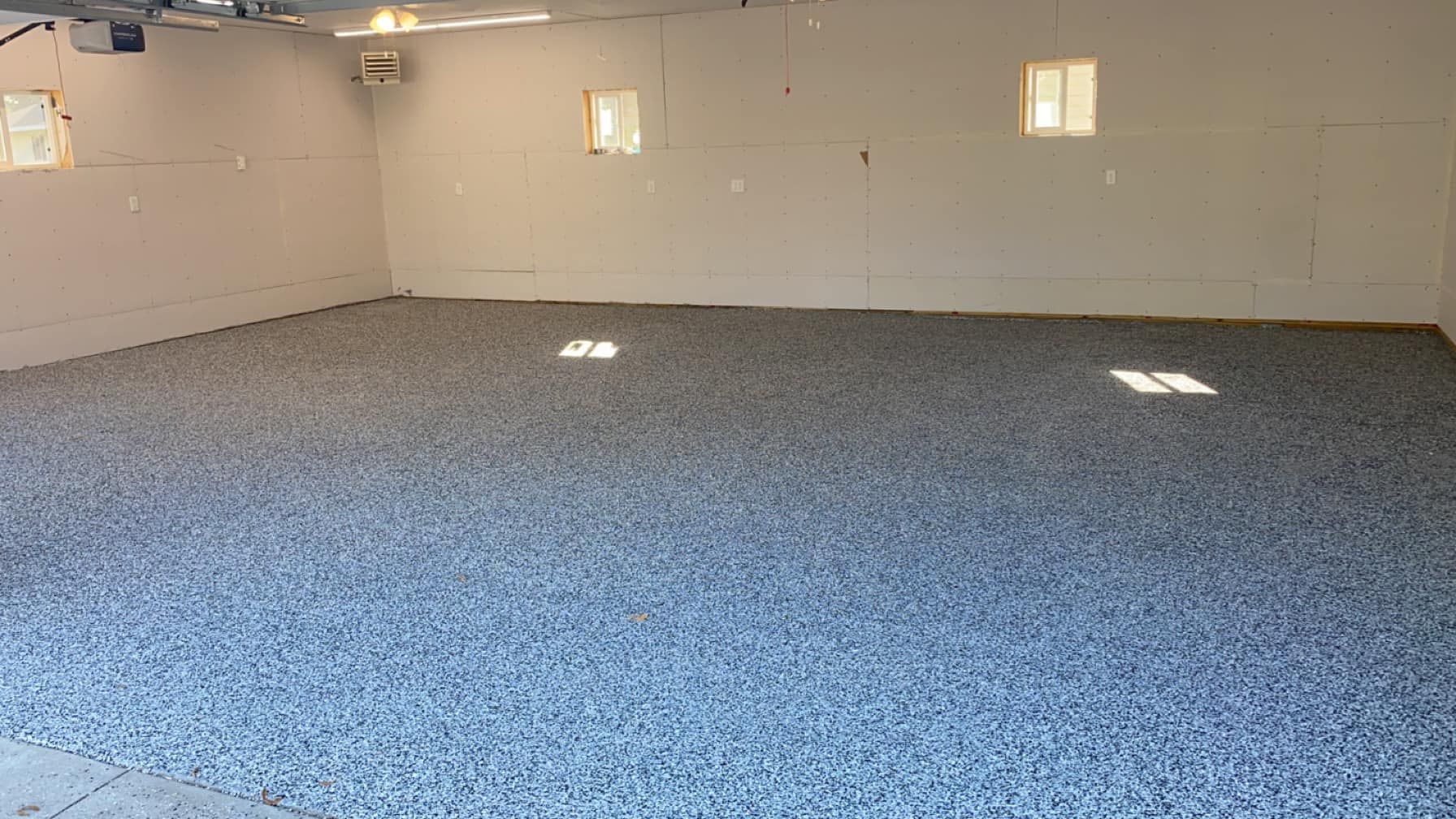 A large empty garage with a gray floor and white walls.