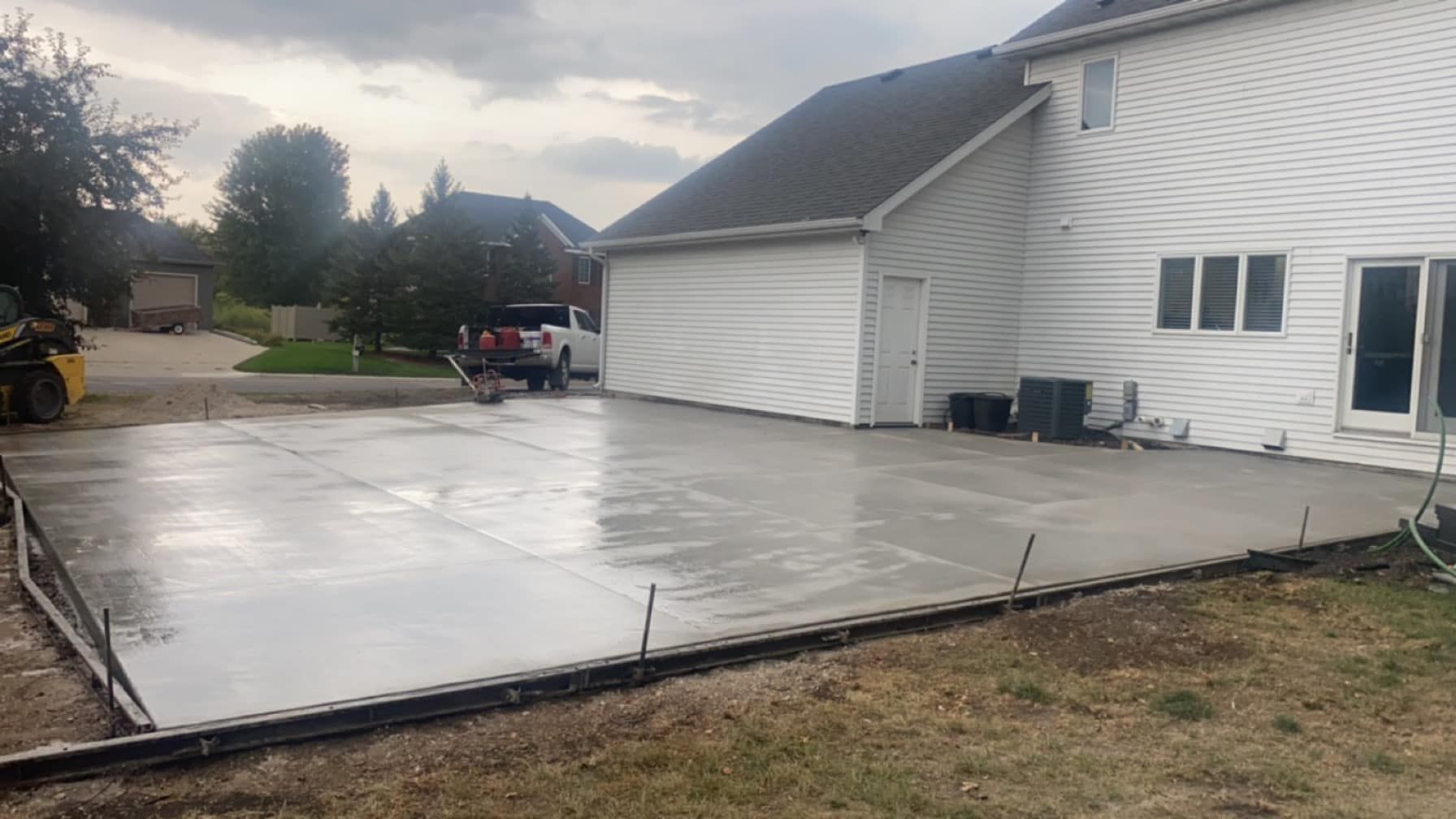A concrete driveway is being built in front of a white house.