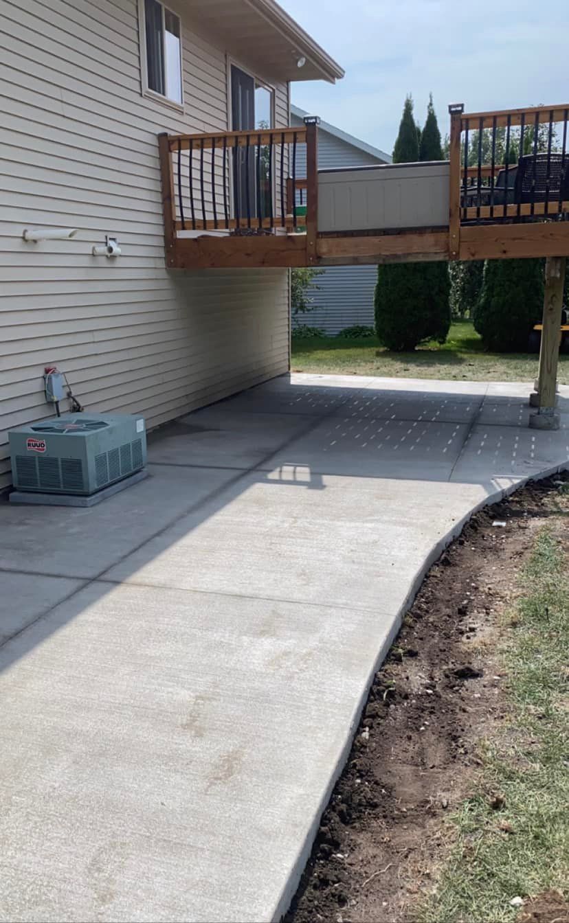 A concrete walkway leading to a house with a deck.
