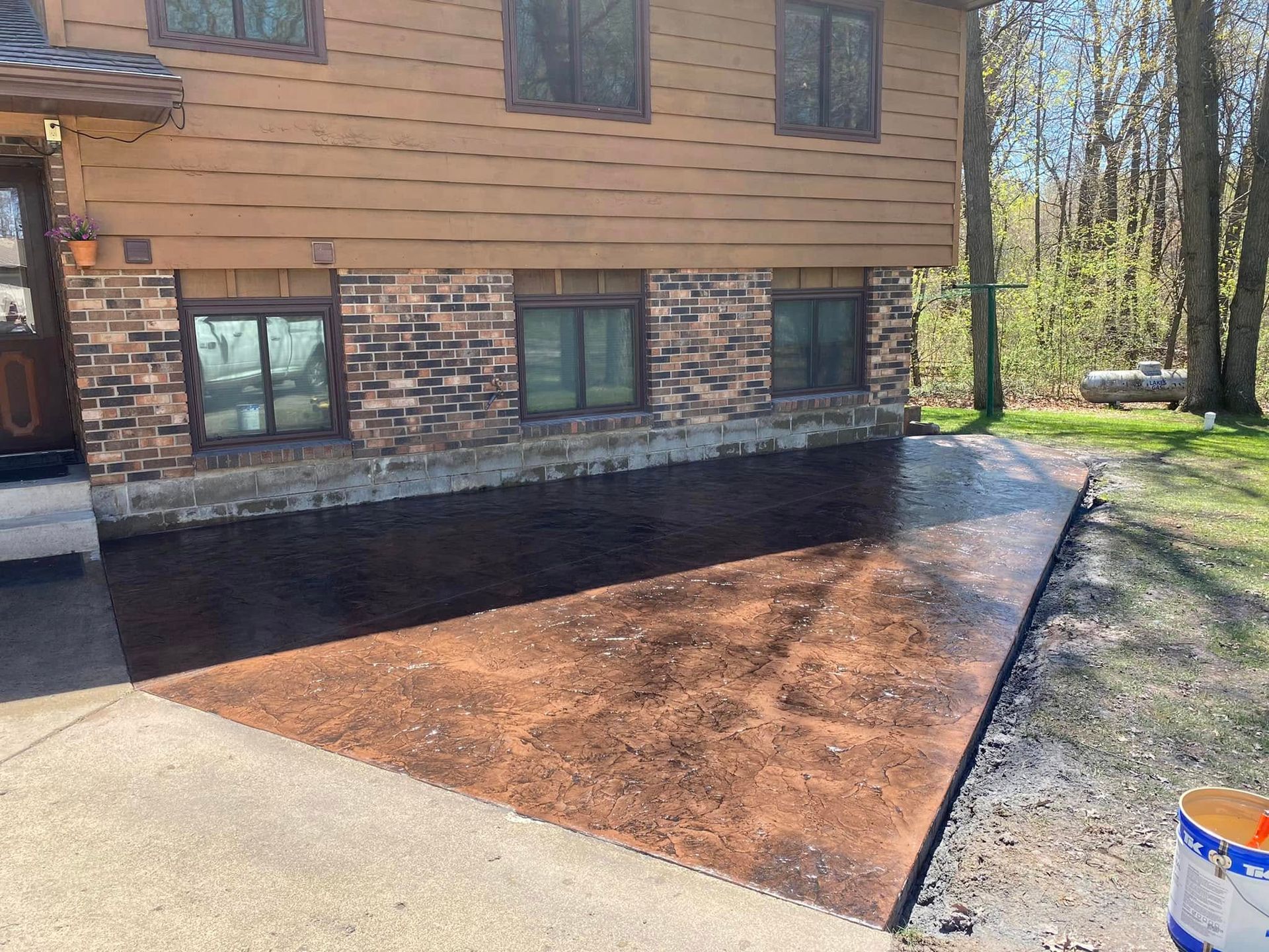 A concrete driveway is being painted in front of a house.