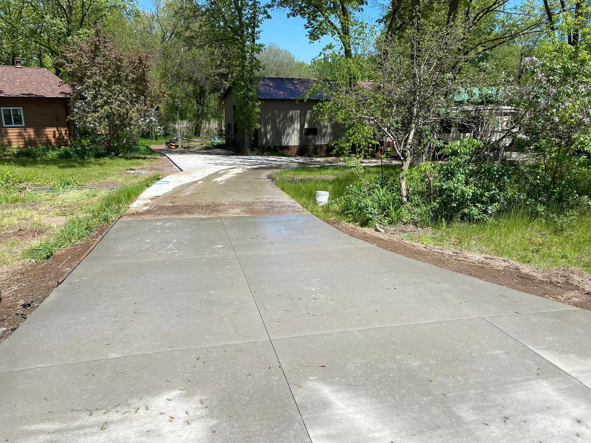 A concrete driveway leading to a house surrounded by trees.