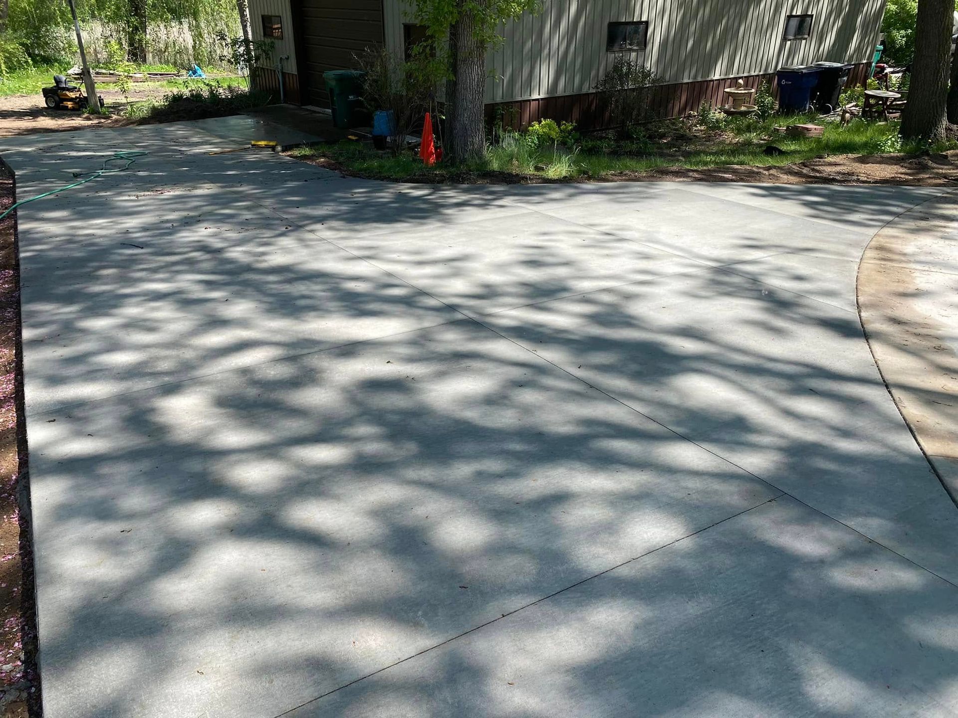 A concrete driveway leading to a house with trees in the background.