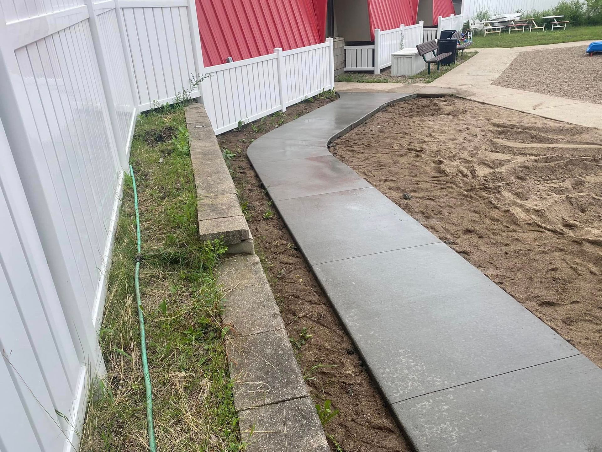 A concrete walkway is being built next to a white fence.