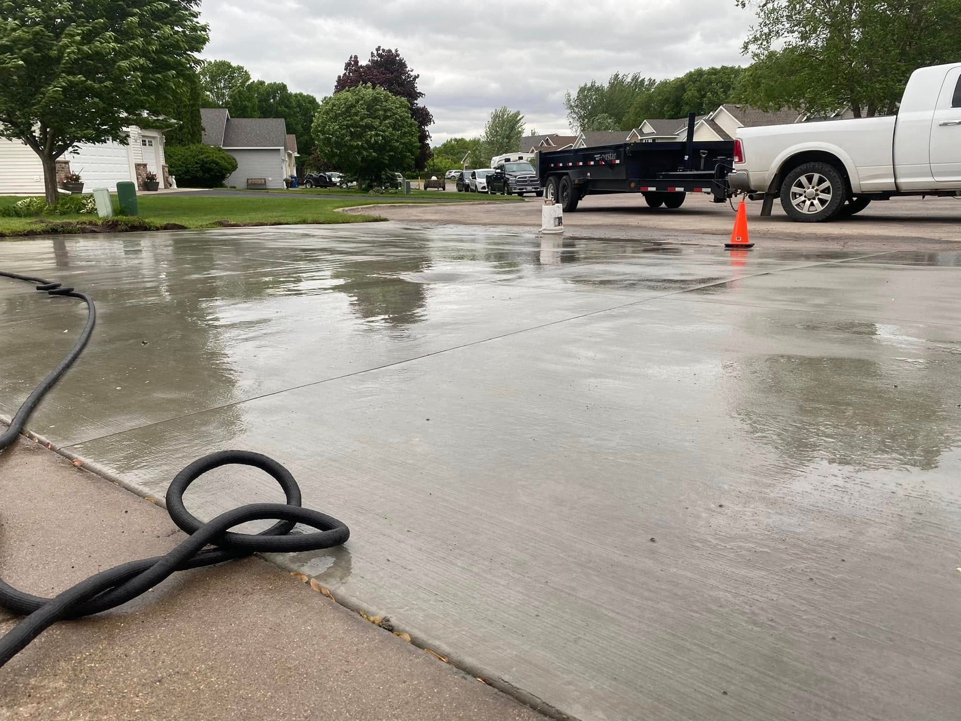 A white truck is parked in a parking lot next to a hose.