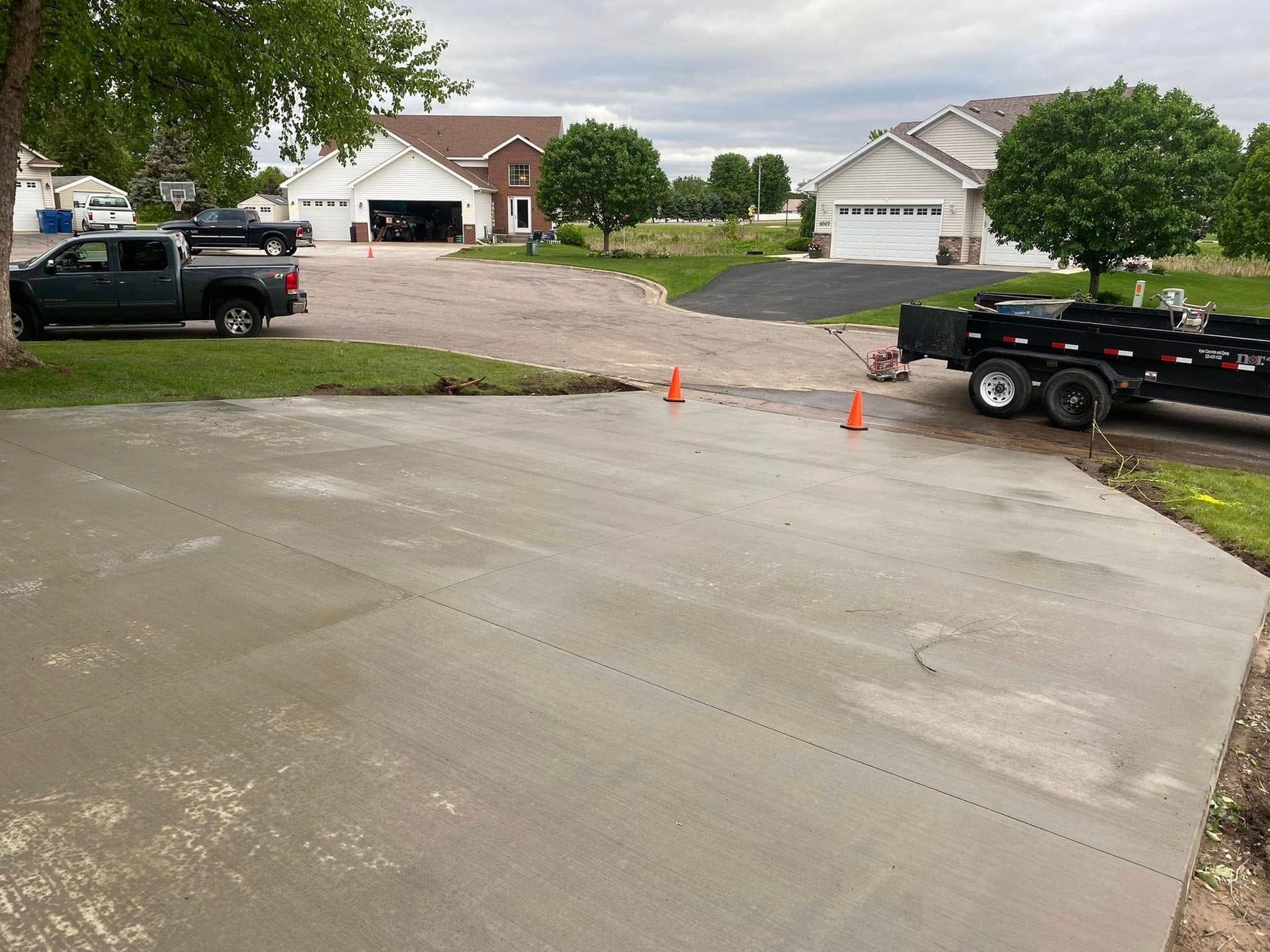 A truck is parked in a driveway next to a trailer.