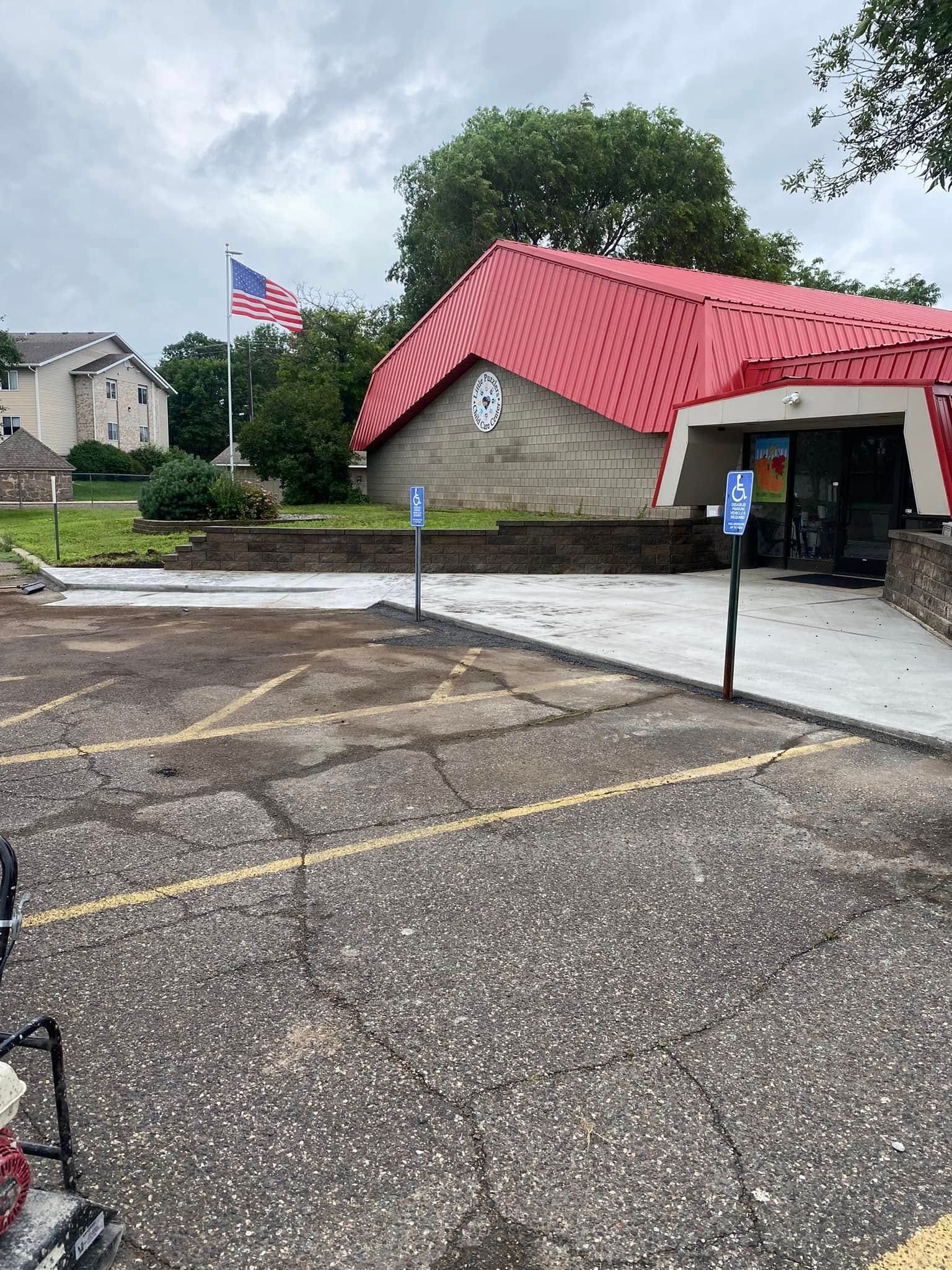 A parking lot in front of a building with a red roof and an american flag.