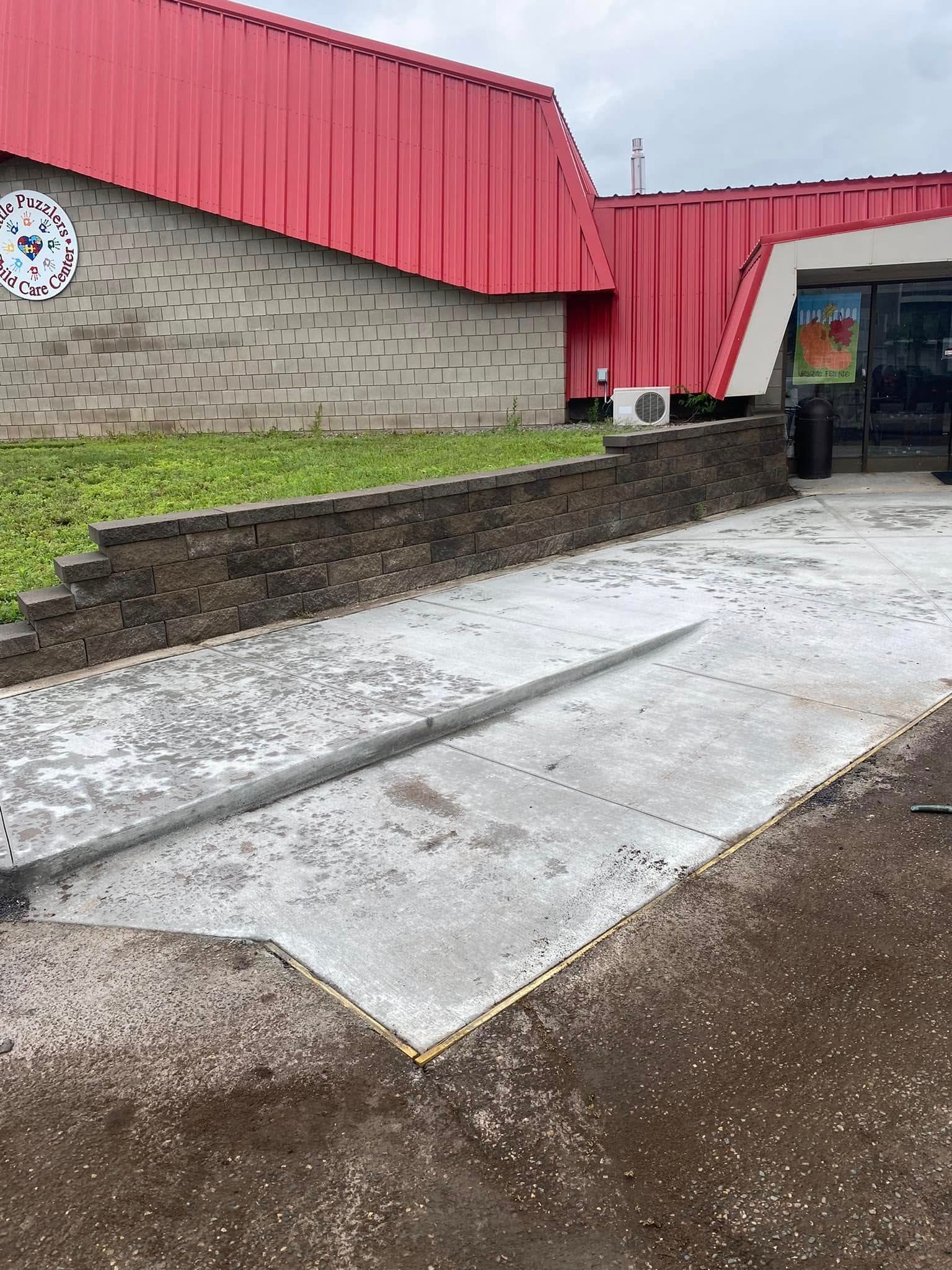 A concrete walkway is being built in front of a building with a red roof.