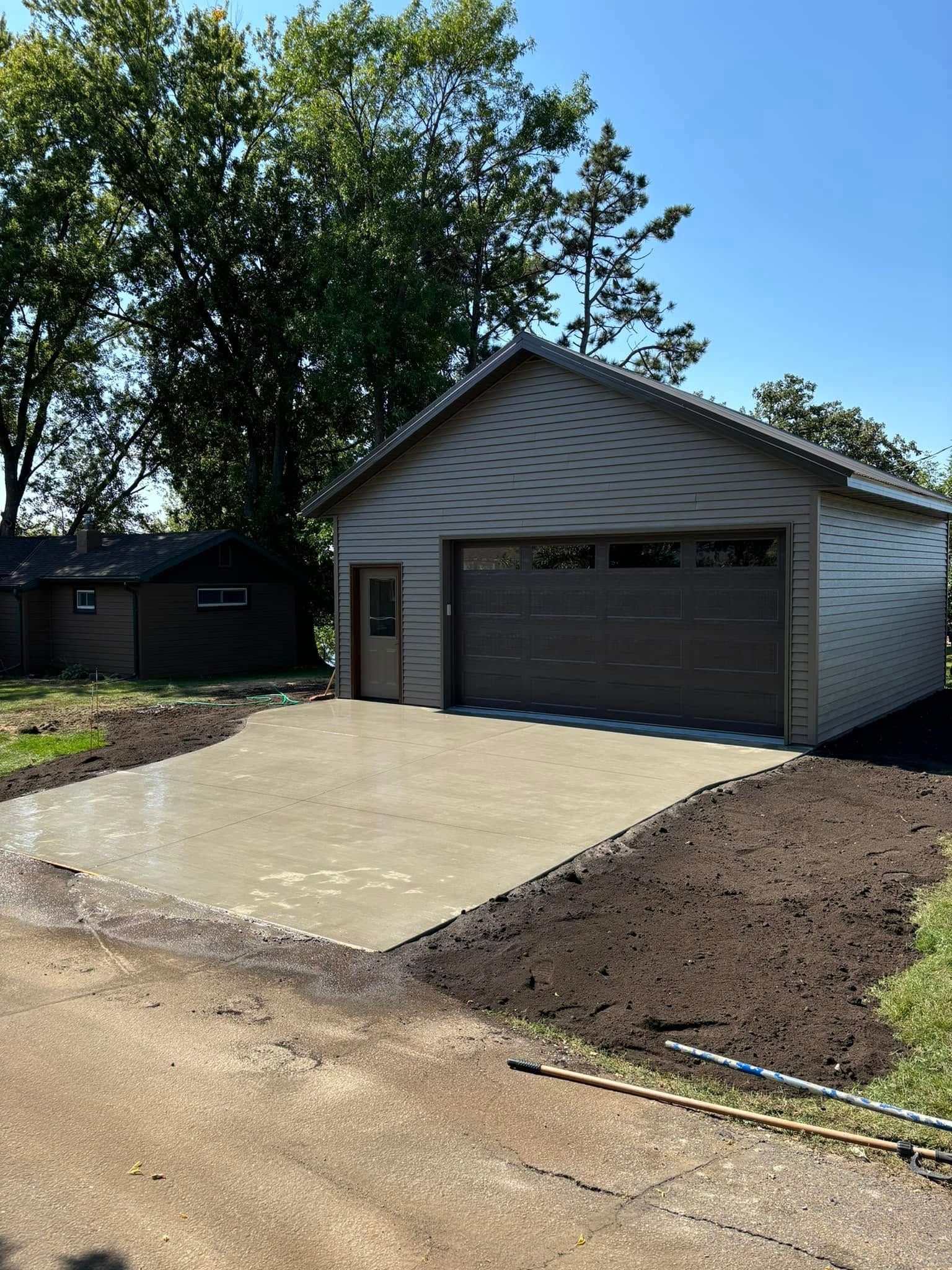 A garage with a concrete driveway in front of it.