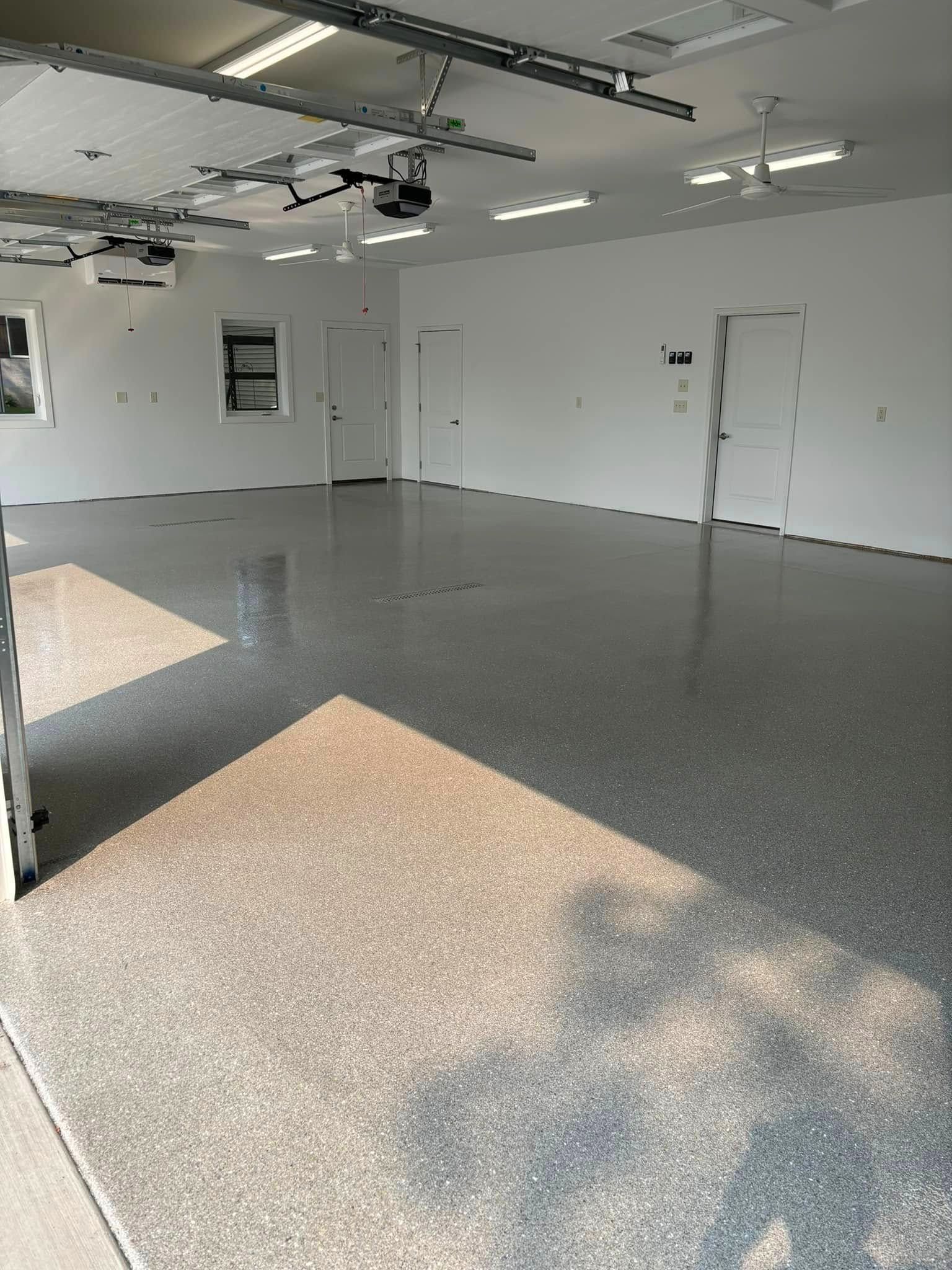 A large empty garage with a gray floor and white walls.